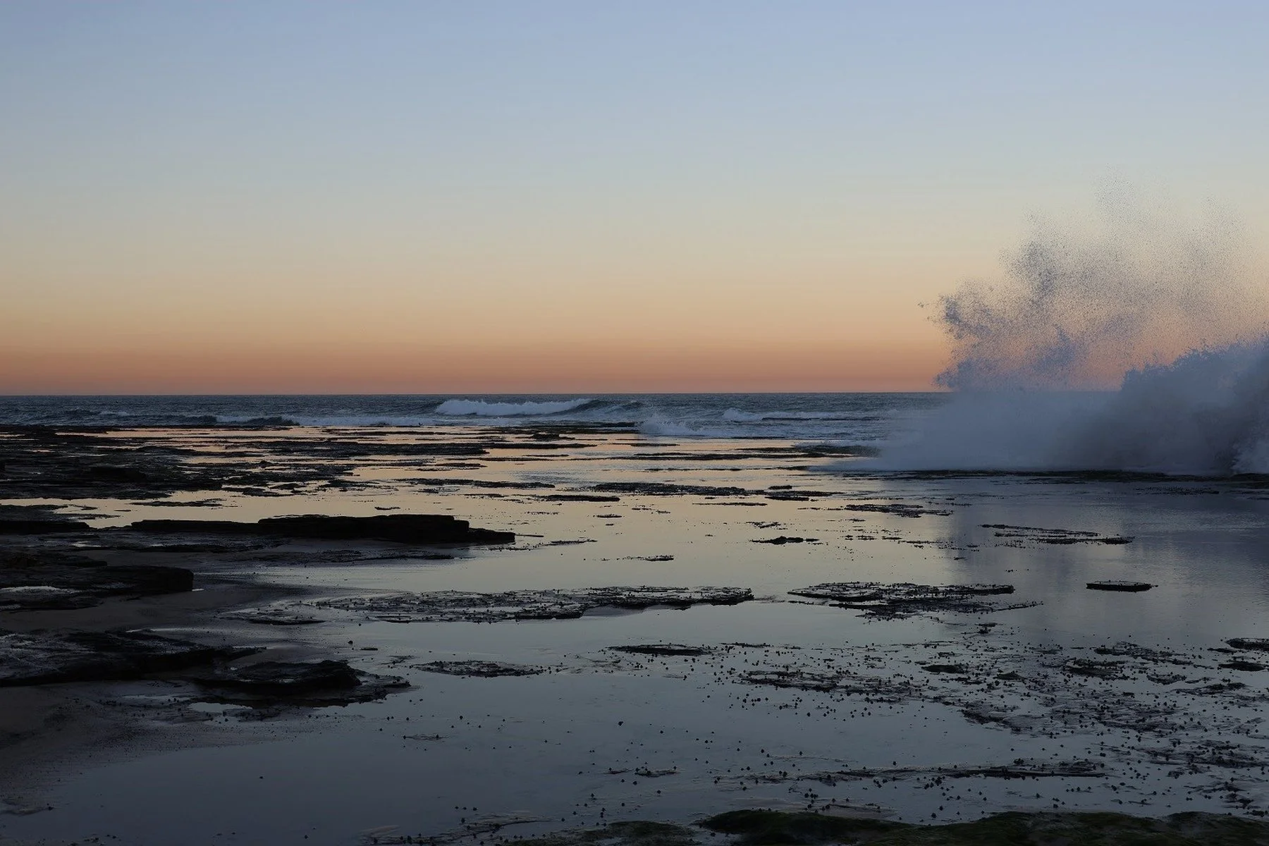 Waves Crashing Over Rock Platforms at Sunset