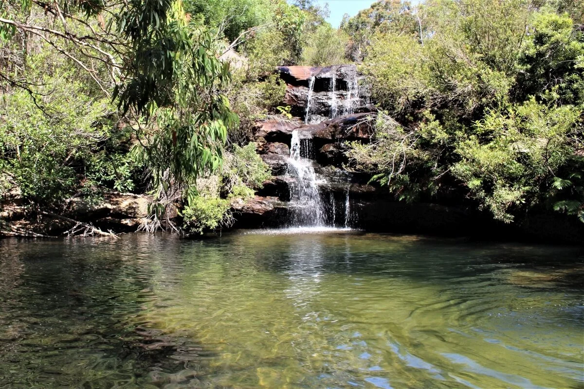 Tiered waterfall dropping into a clear green swimming hole at Curracurrong, Royal National Park