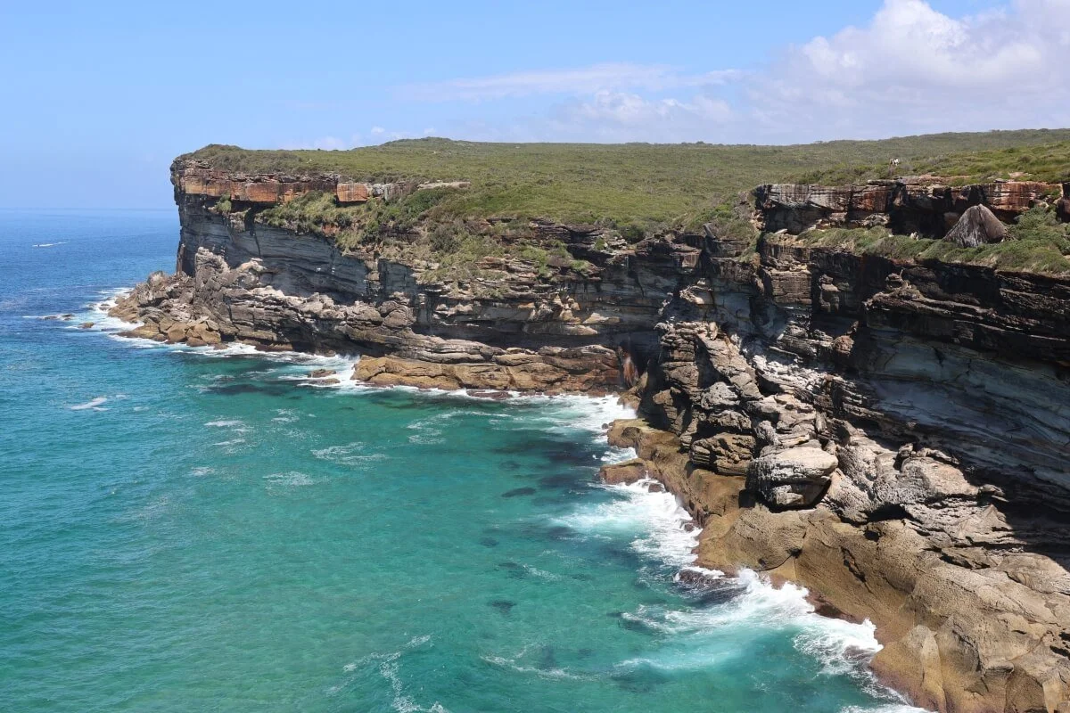 Turquoise bay with layered sandstone coastal cliffs at Curracurrong Creek, Royal National Park