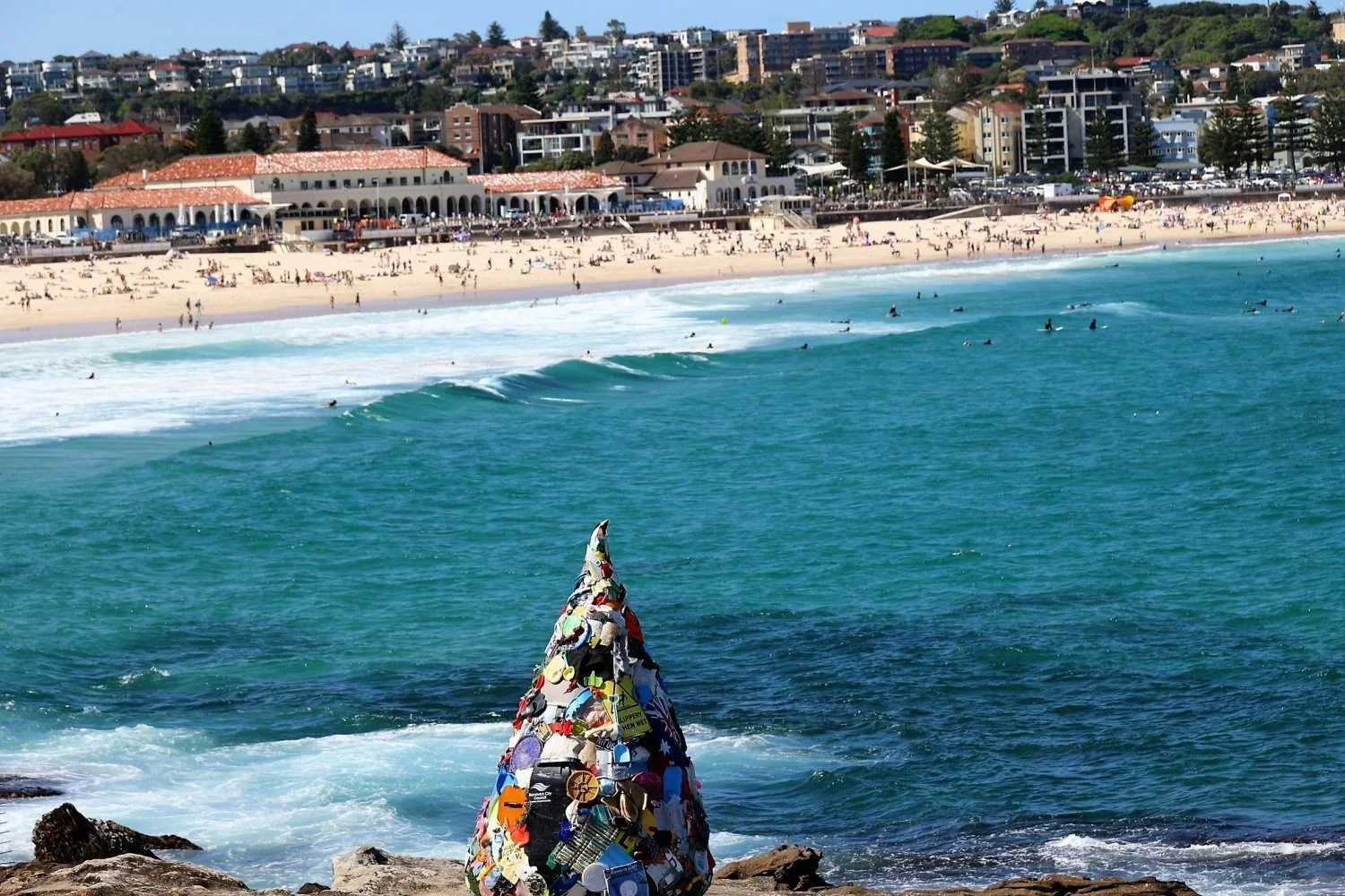 Sculpture made from collaged objects on the Bondi headland with Bondi Beach panorama behind, Sculptures by the Sea