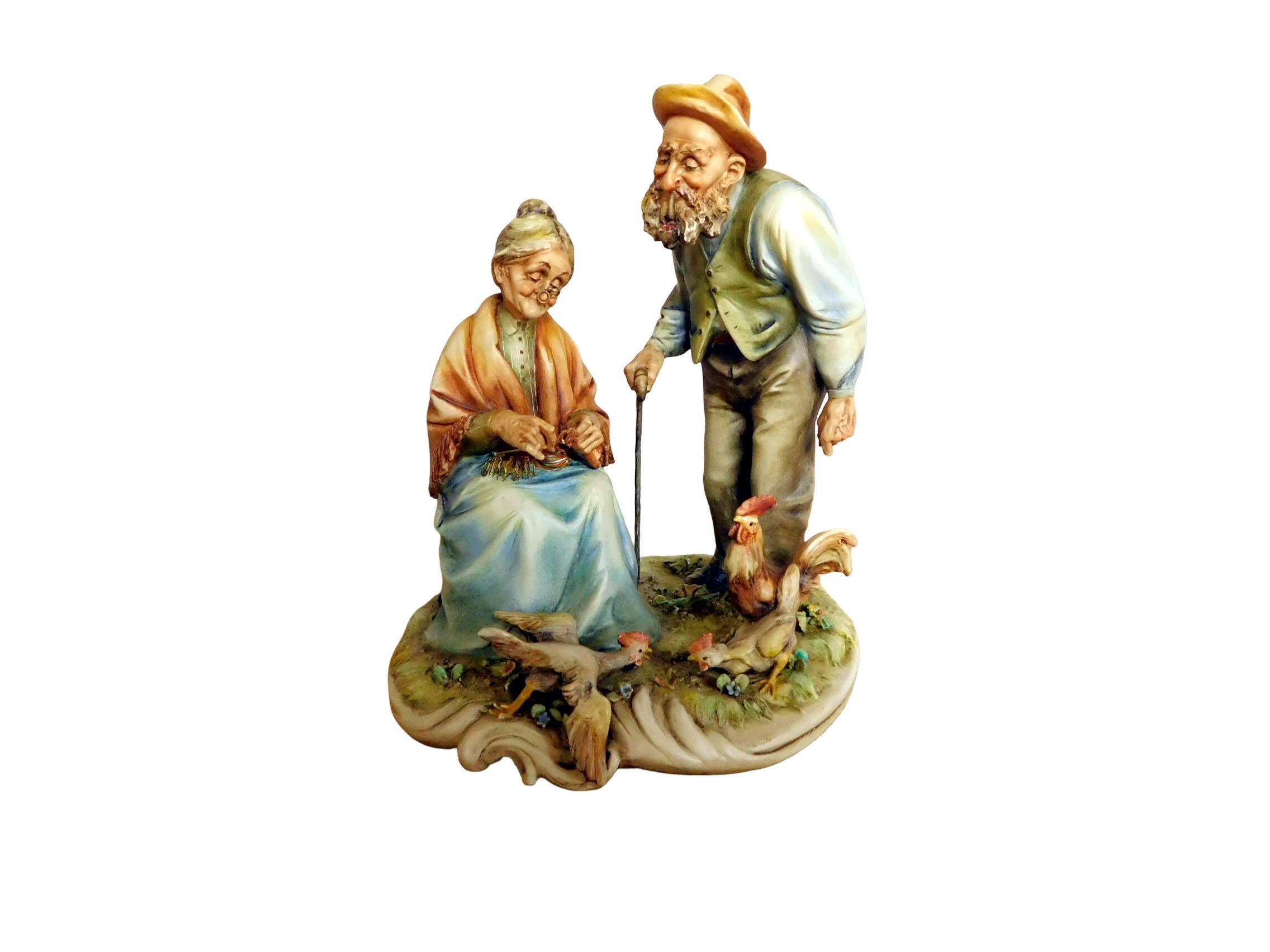 Antonio Borsato fine porcelain figurine or an elderly couple outside.  The man is standing with a can looking over the woman's shoulder..  The woman is seated.