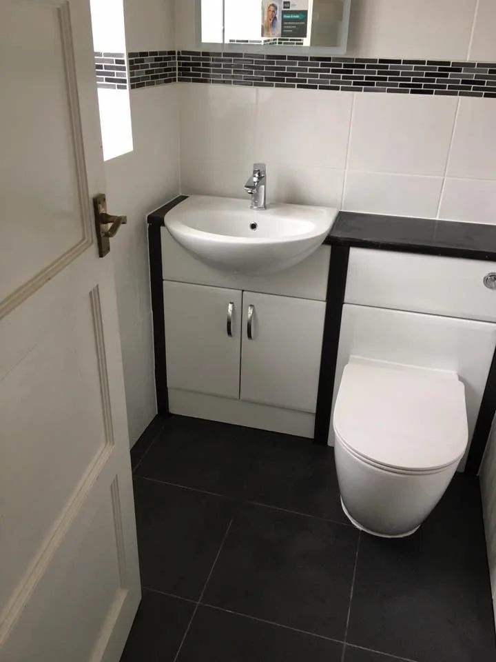 Clean, new bathroom design with mosaic tile border, toilet and bathroom cabinet sink unit