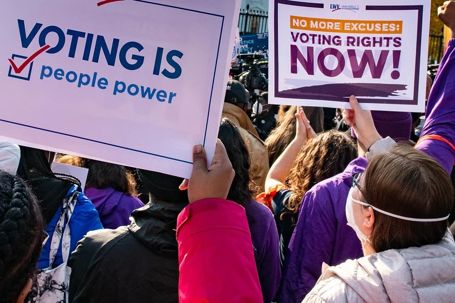 a group of people holds signs in support of voting rights