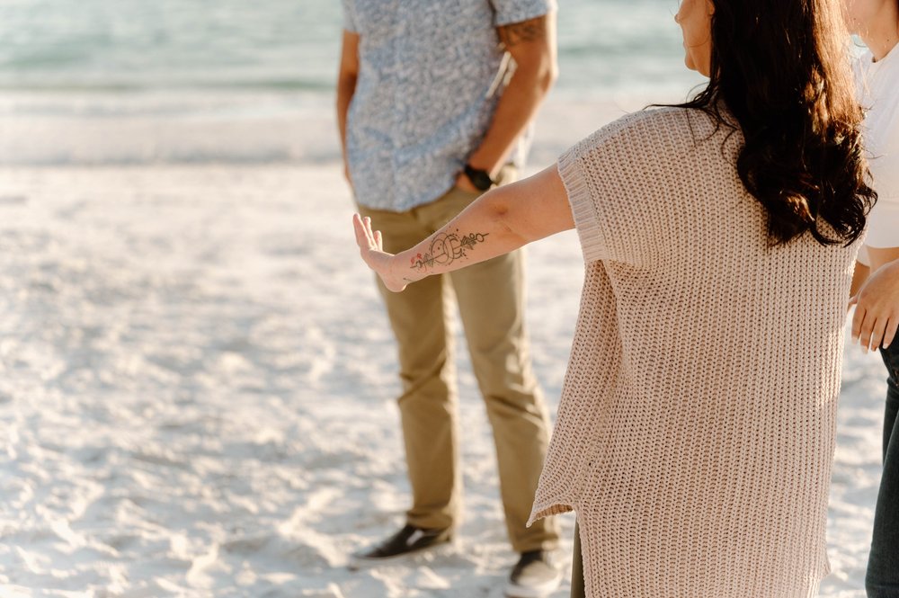  A woman admires her new engagement ring while standing on a beach 