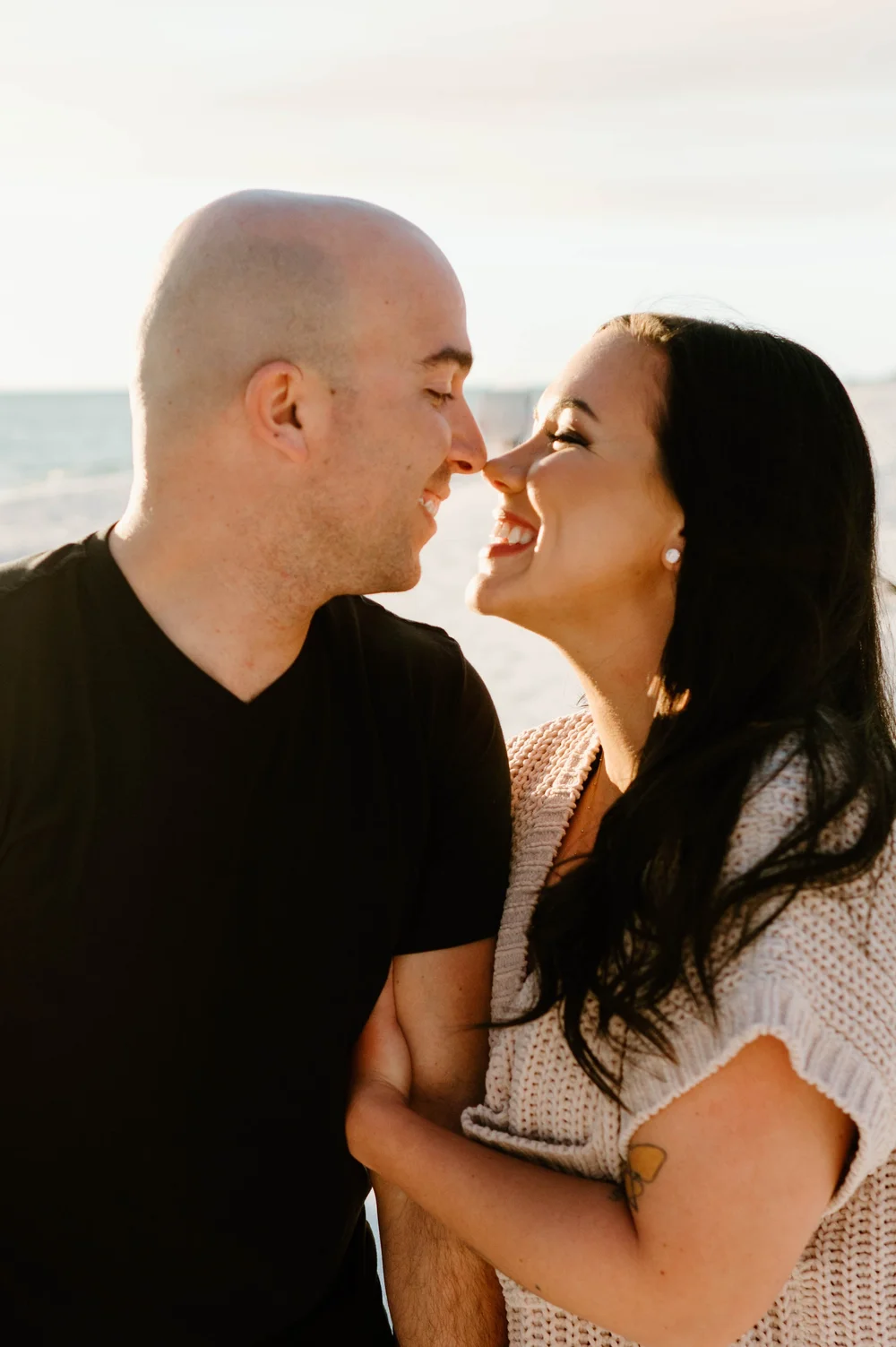  A happy smiling couple touch noses while walking on a beach at sunset during their 30A Proposal 