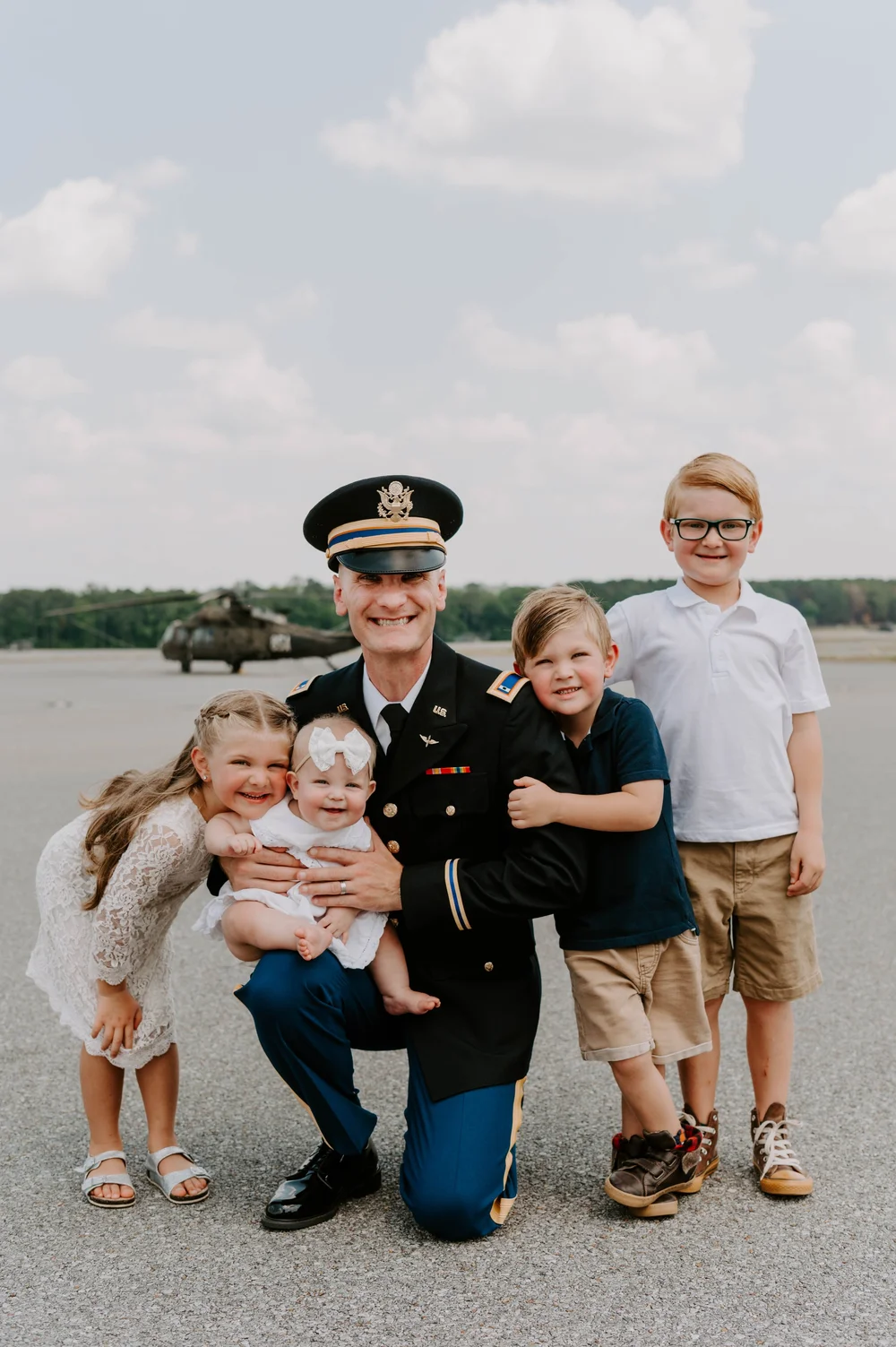  A proud dad hugs his four young children on an airfield after his Military Graduation 