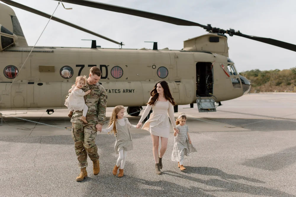  A happy family walks hand in hand by a Chinook celebrating dad's Military Graduation 