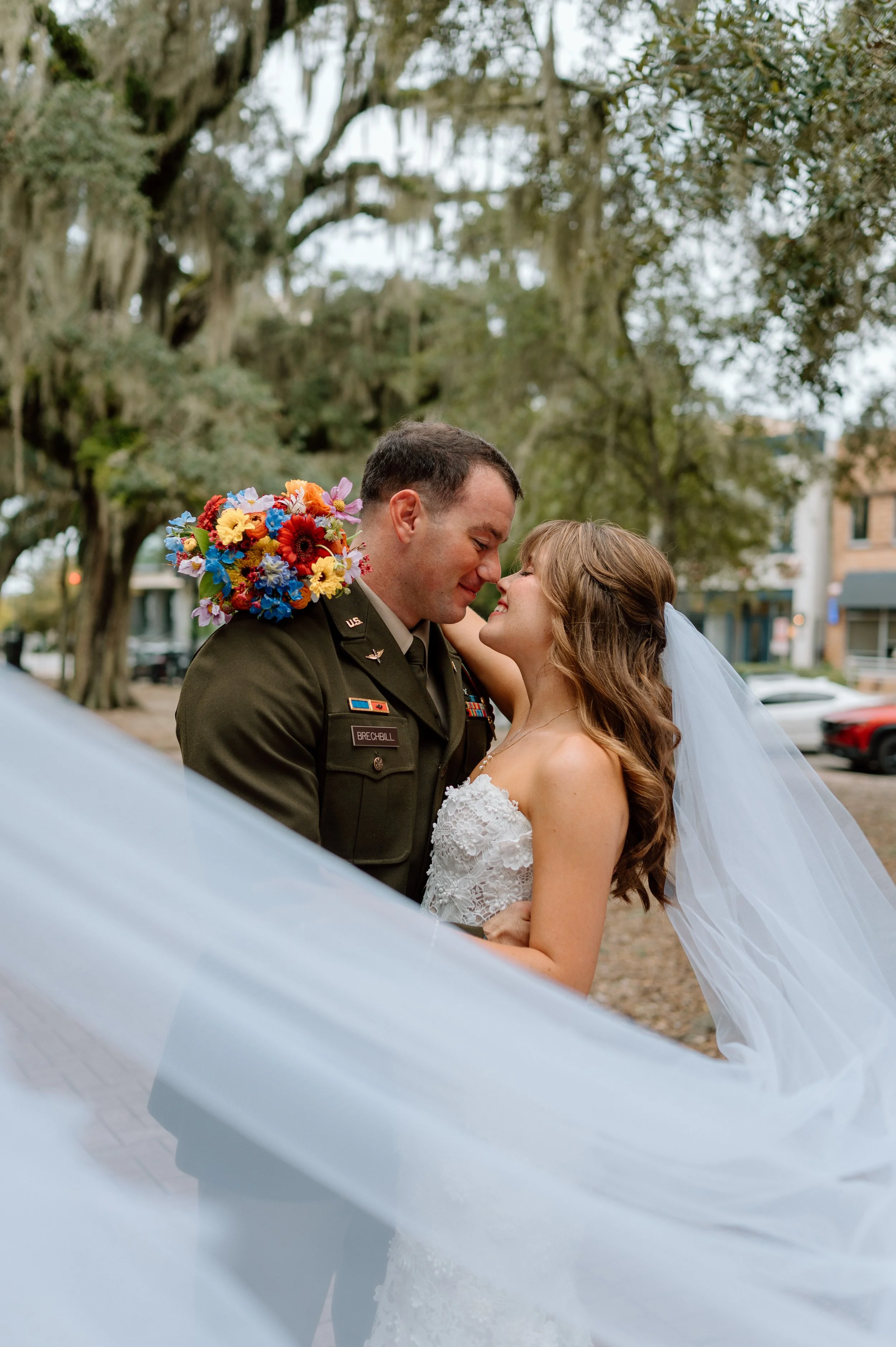 A couple embracing in a park with veil wrapped around them.