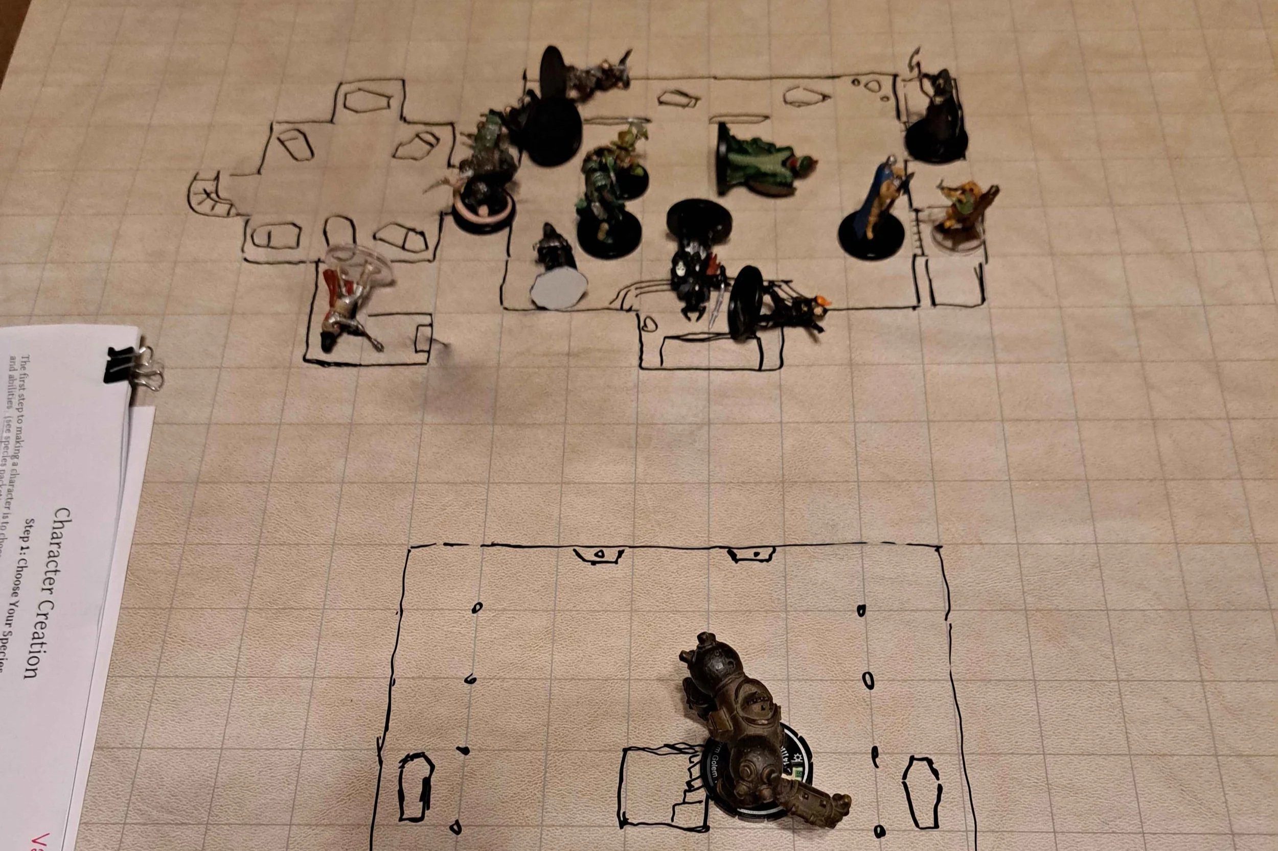 A photo of a playmat with tabletop gaming minitures and a drawn dungeon map.
