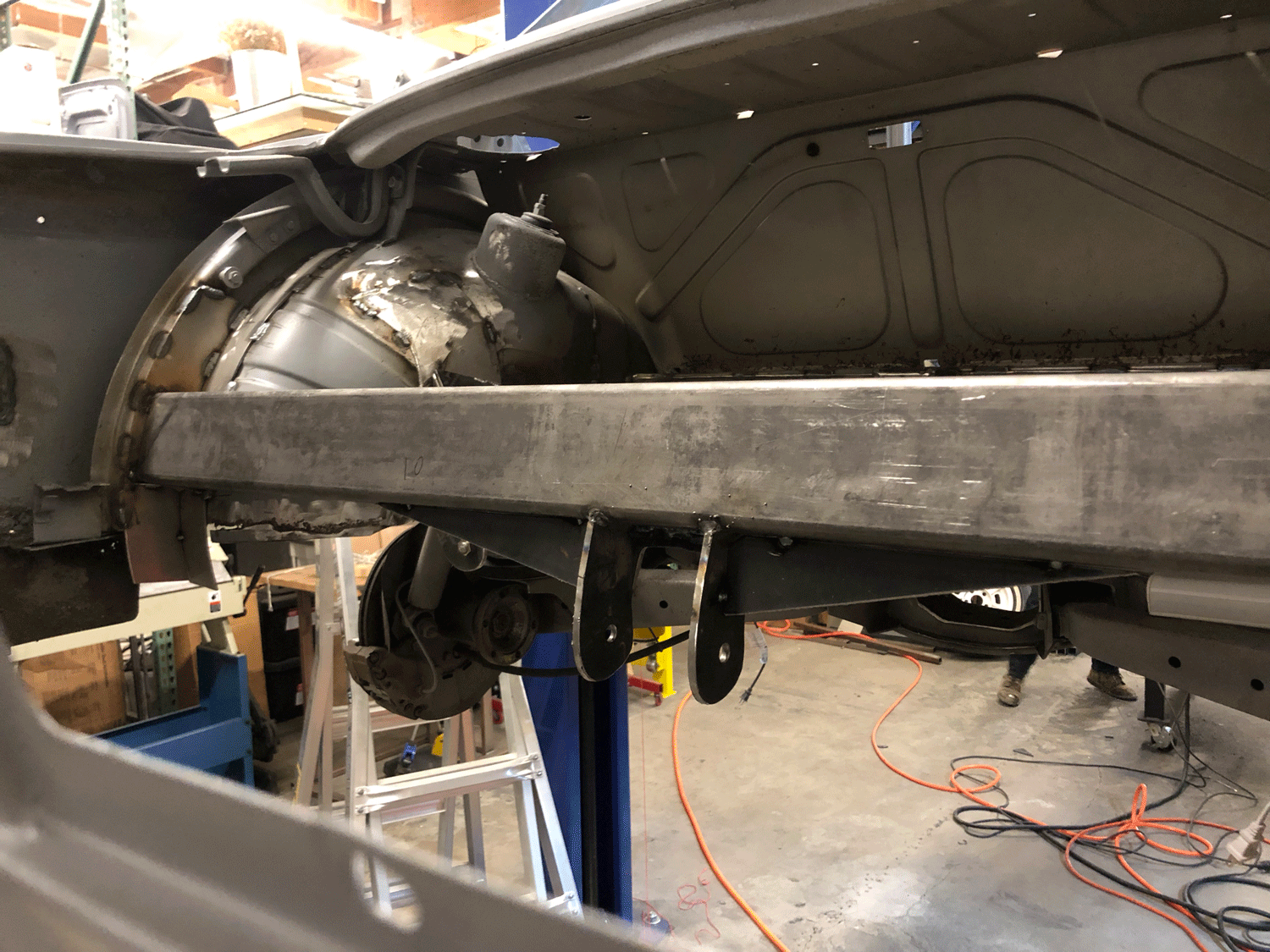 The rear mount suspends from a beam which spans between the wheel wells.