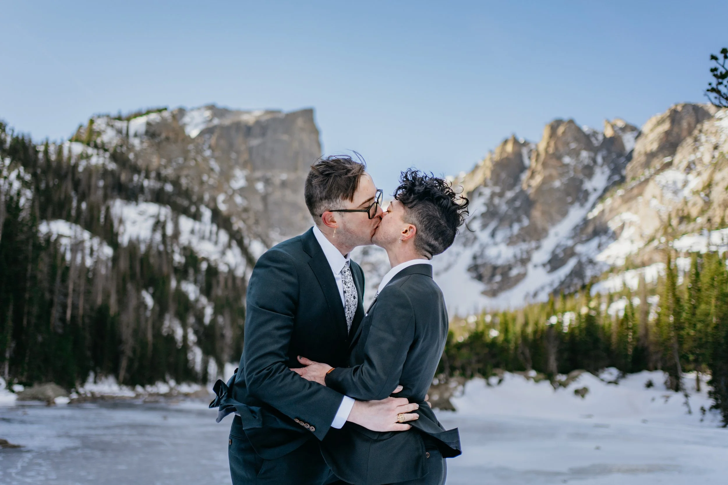 A groom and groom kissing at bear lake in rocky mountain national park colorado usa