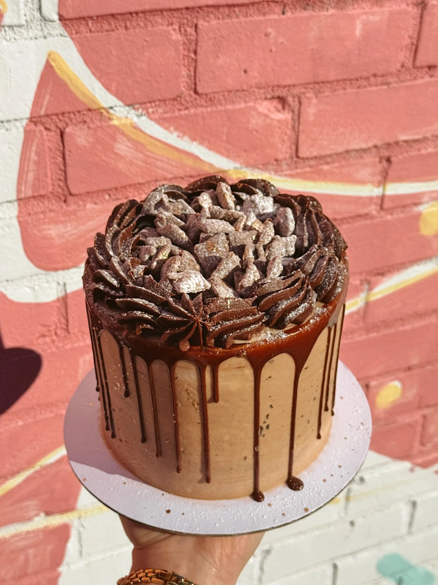 Ya know how we mentioned a new cake flavor this week? Well here she is in all her glory!!! 
MEET THE PUPPY CHOW CAKE 🤤🥜🍫
Our signature yellow cake w/ chocolate peanut butter buttercream, topped w/ our puppy chow &amp; chocolate ganache drizzle! Av