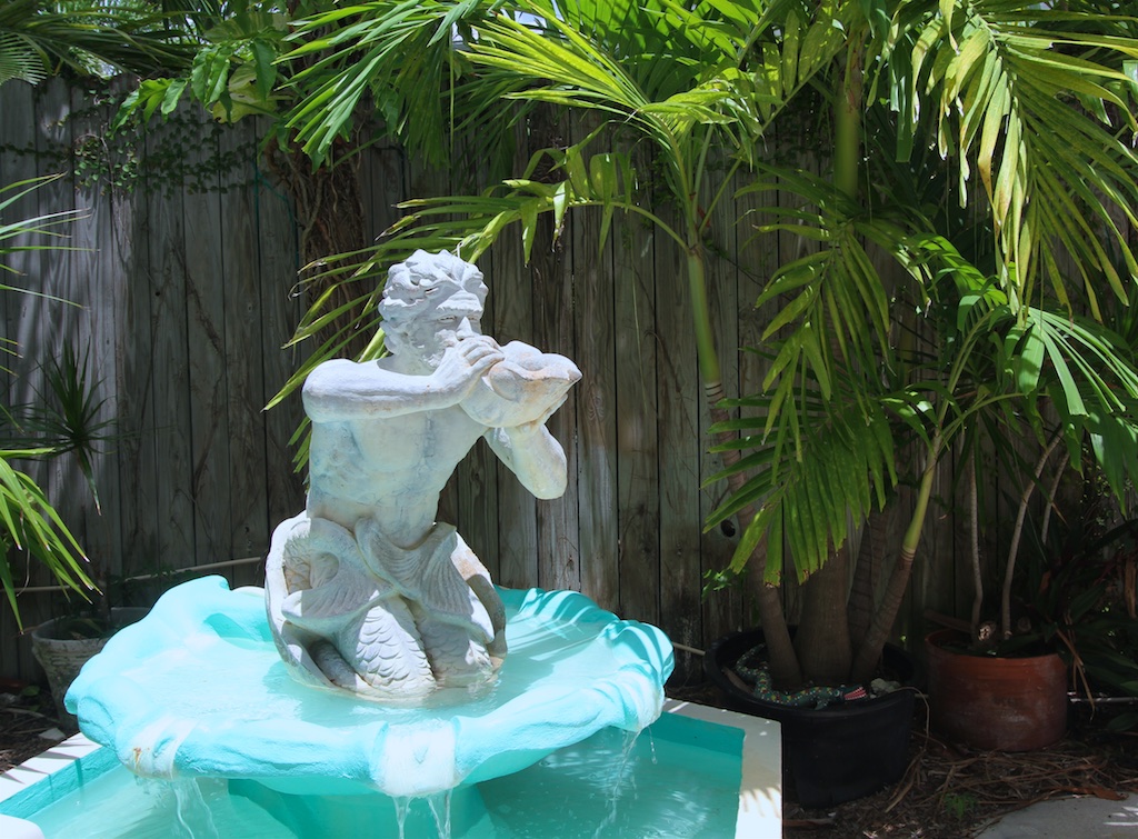 pool sculpture. man blowing on a conch shell.