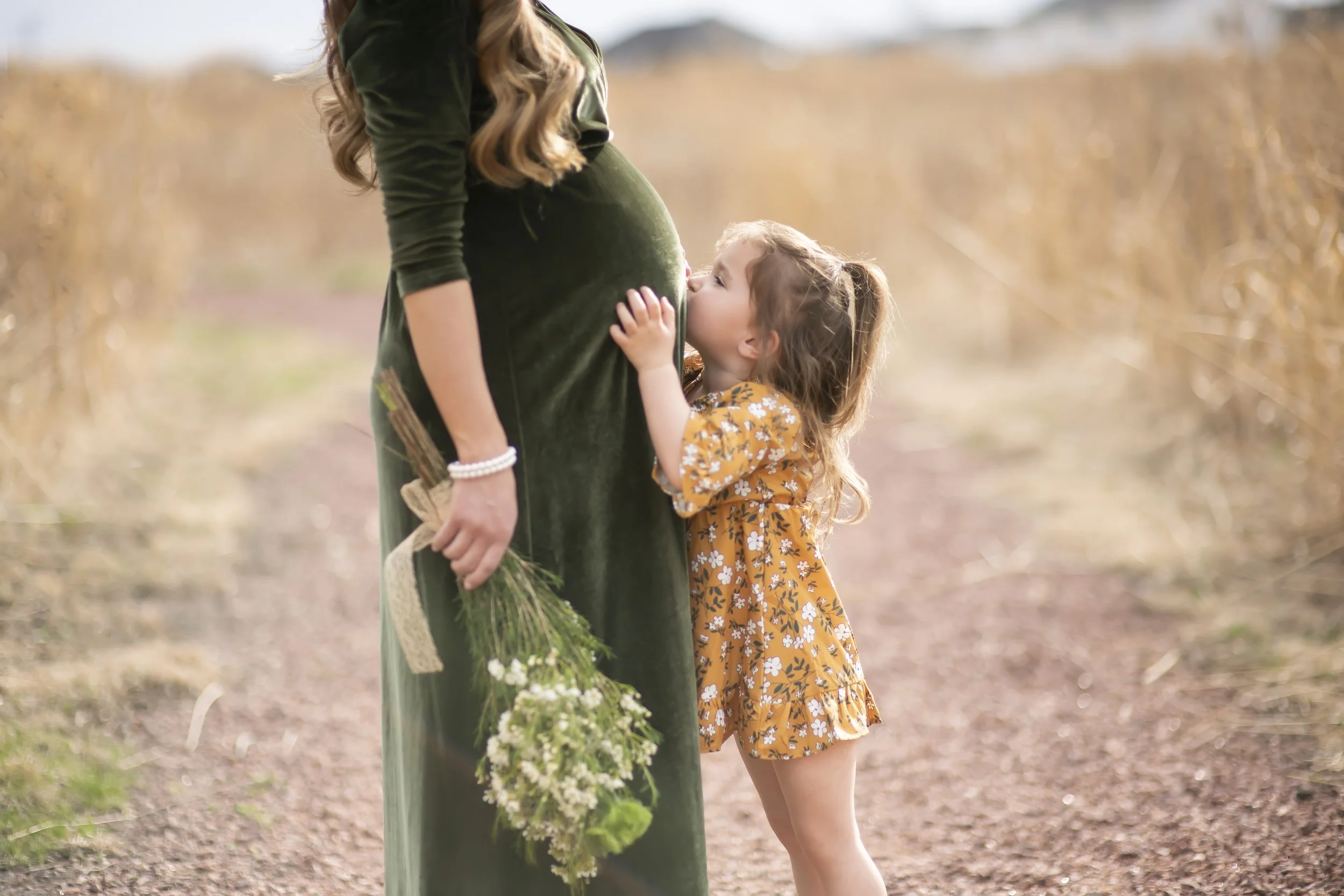 Big sister kissing baby bump in maternity session.jpg