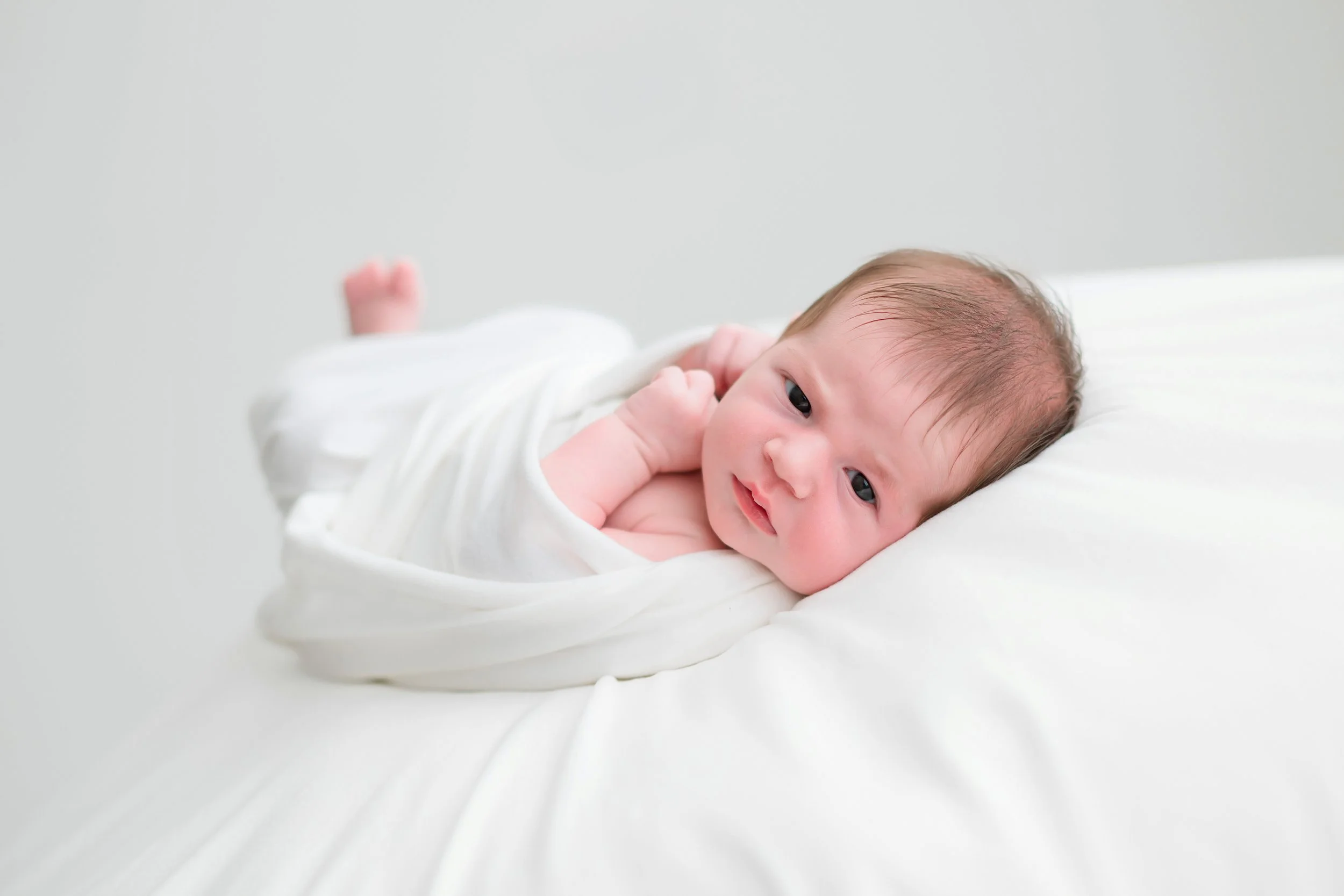 Newborn in white studio space awake
