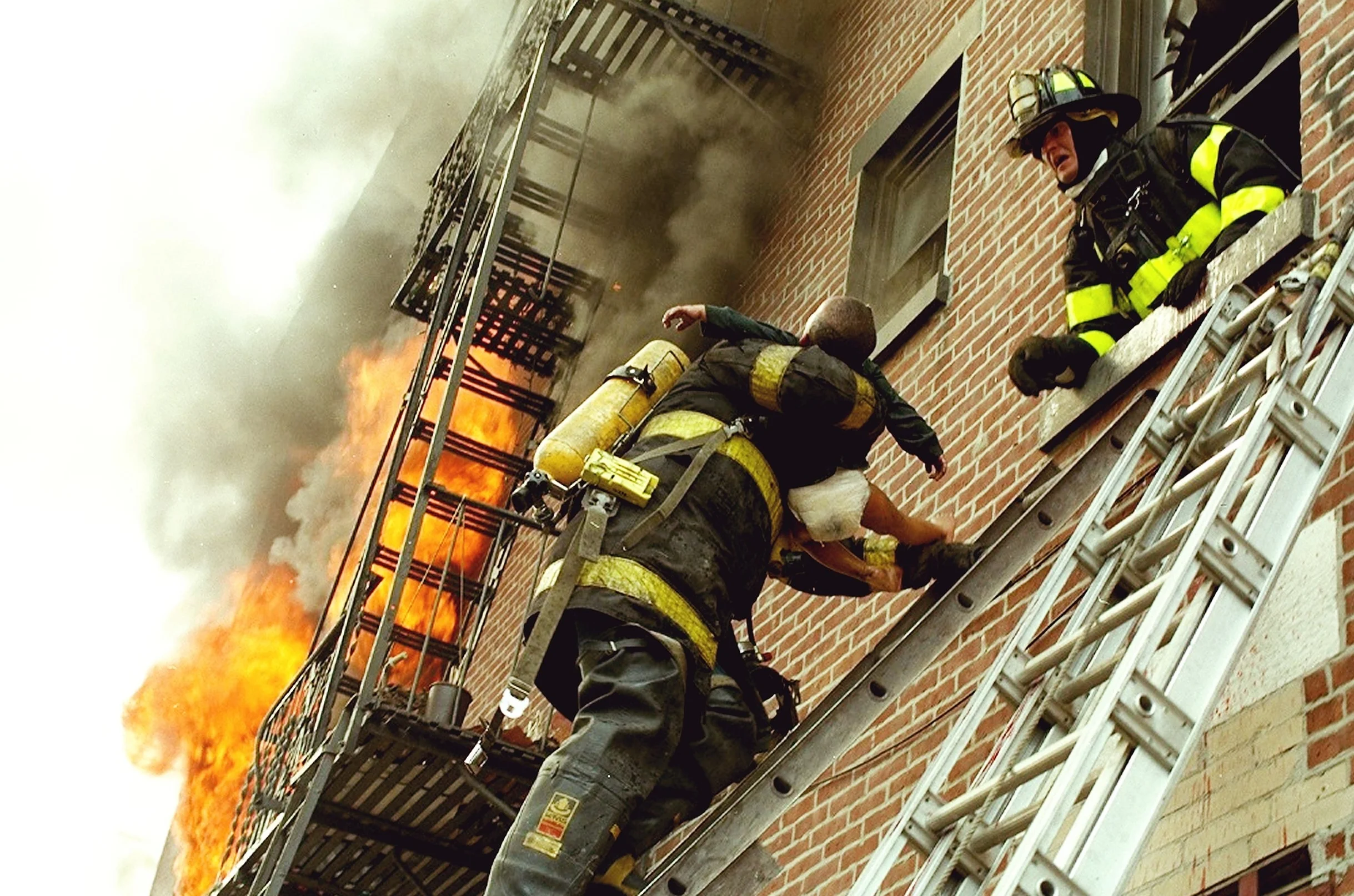 Firefighters rescue a child from a burning apartment in Red Hook Brooklyn June 1993 during a two-alarm fire. Two people were killed in the blaze and several were rescued including the young boy. By Todd Maisel