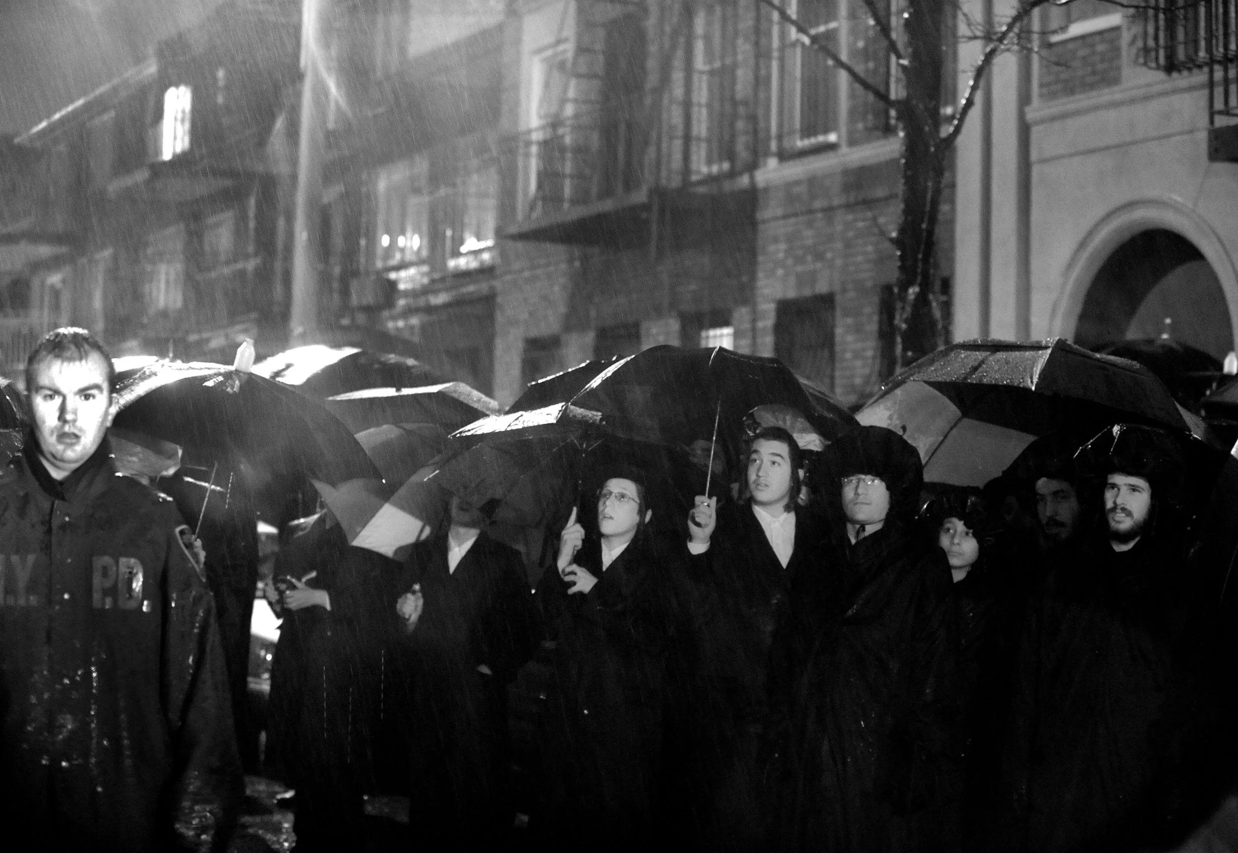  Residents of Borough Park stay behind a New York City police officer during a heavy rain as they watch a two alarm fire in a large home December 11, 2008. By TODD MAISEL, NY DAILY NEWS 