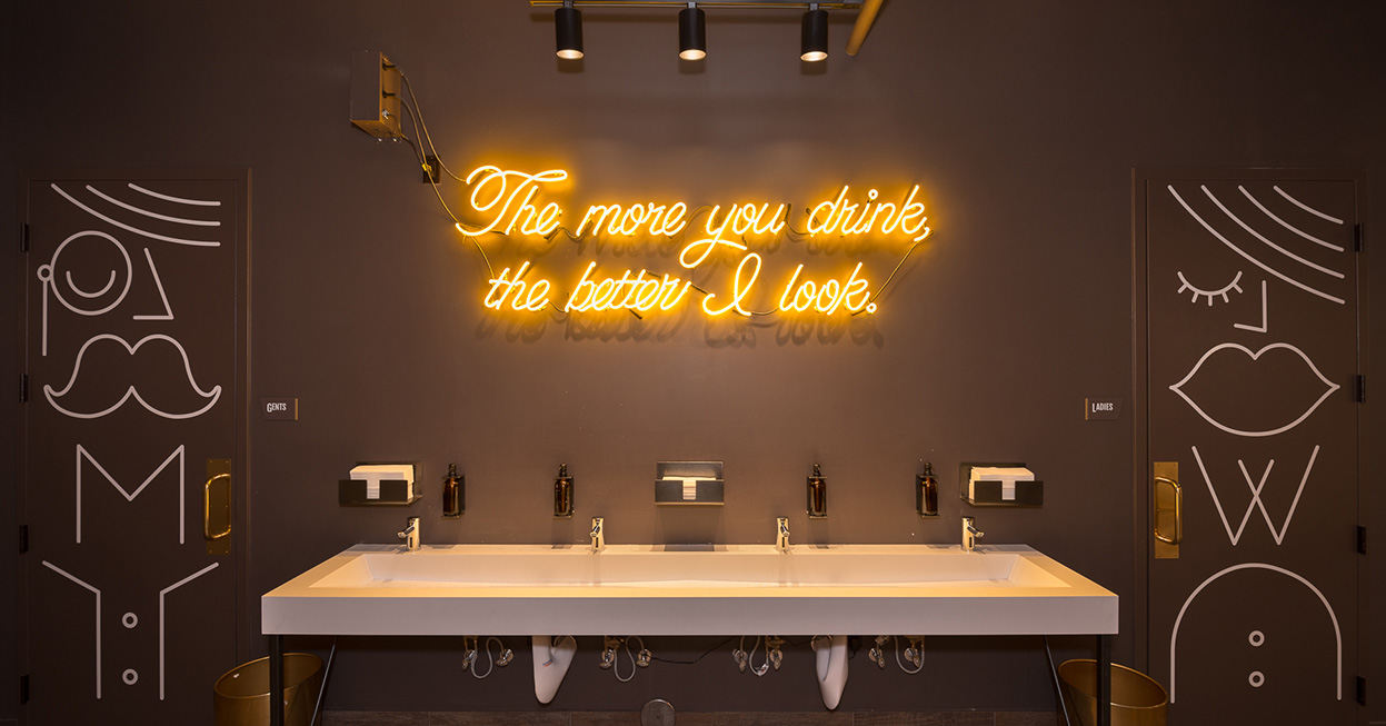Custom neon sign in bathroom area of brewery remodel by Christian Dean Architecture.