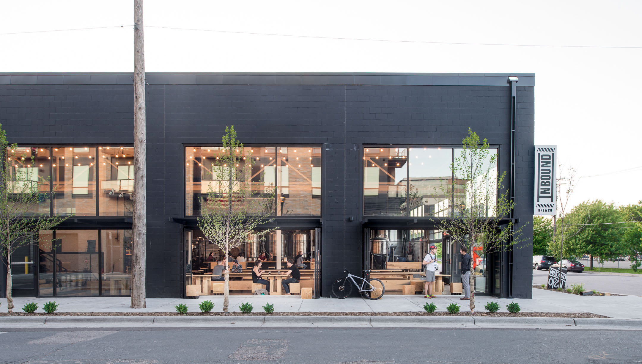 Black painted brewery space in Minneapolis with large windows and garage doors.