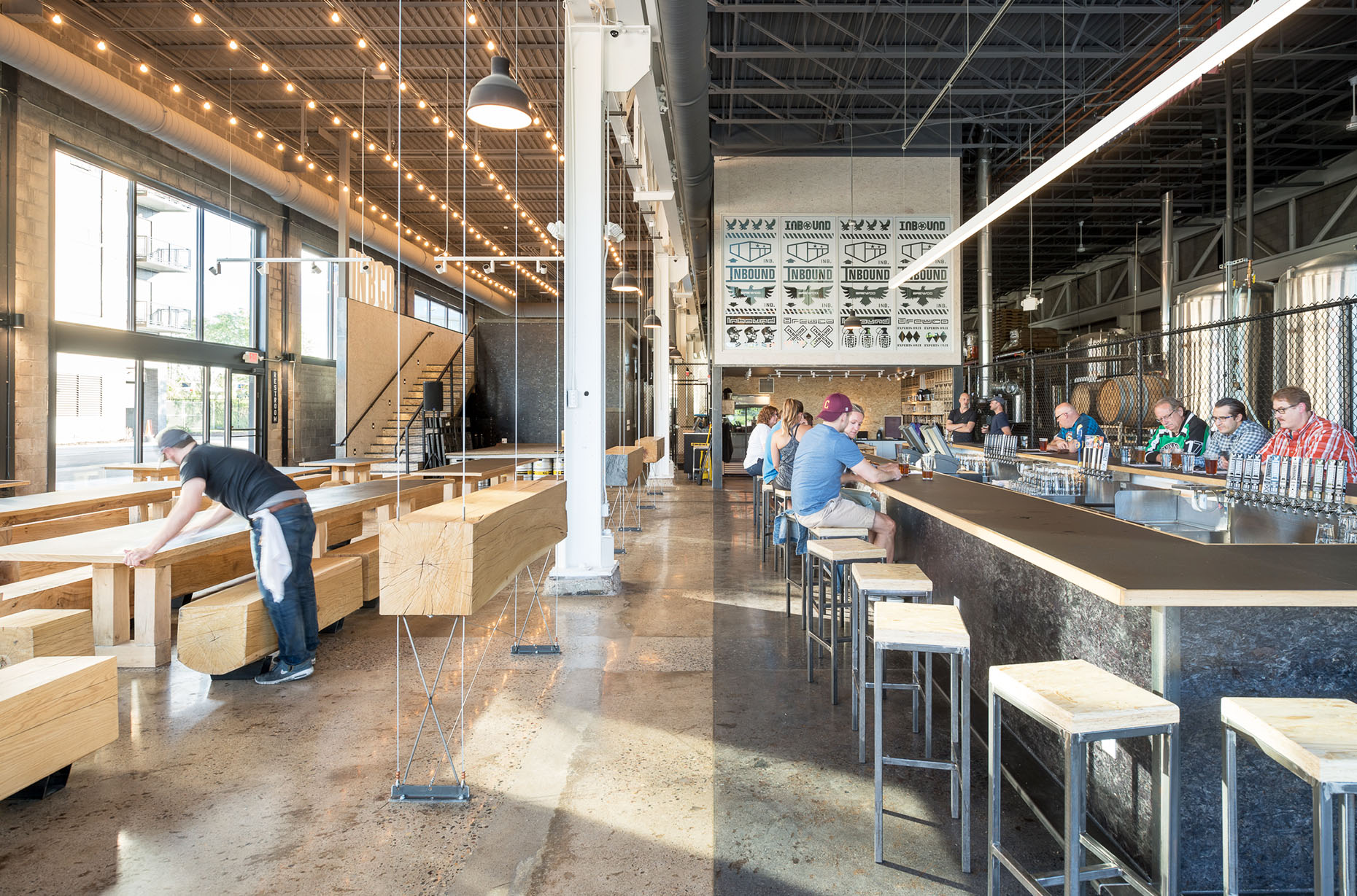 Modern industrial brewery with custom wood tables and standing drink rails.