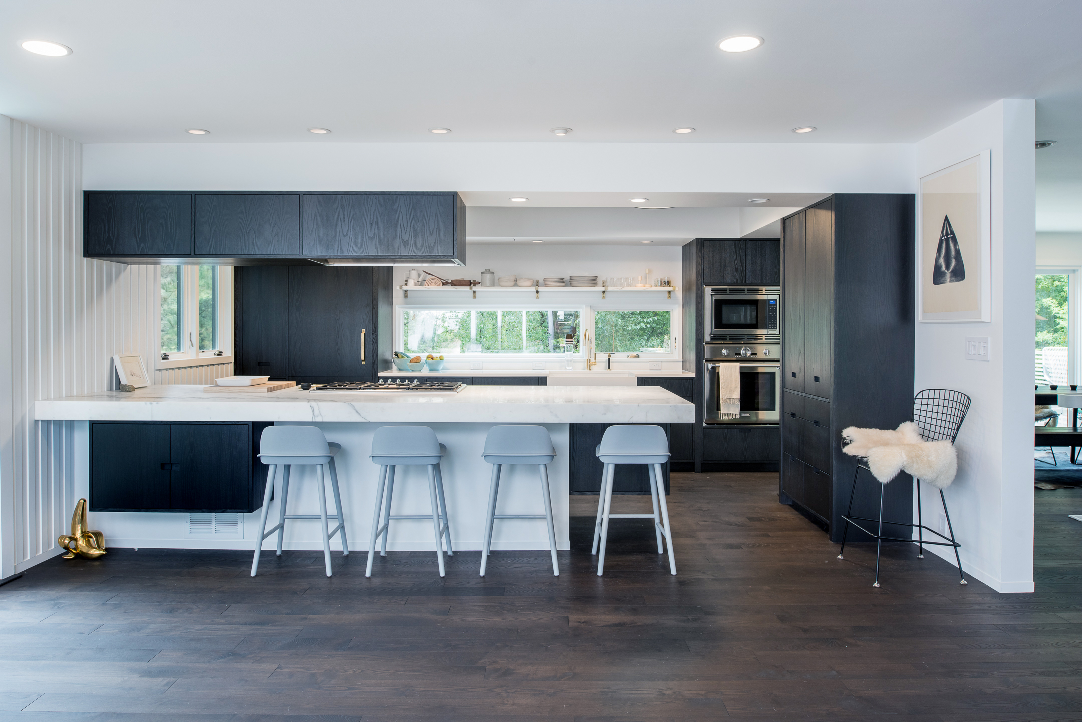 Modern kitchen renovation with black stained cabinetry and marble countertop