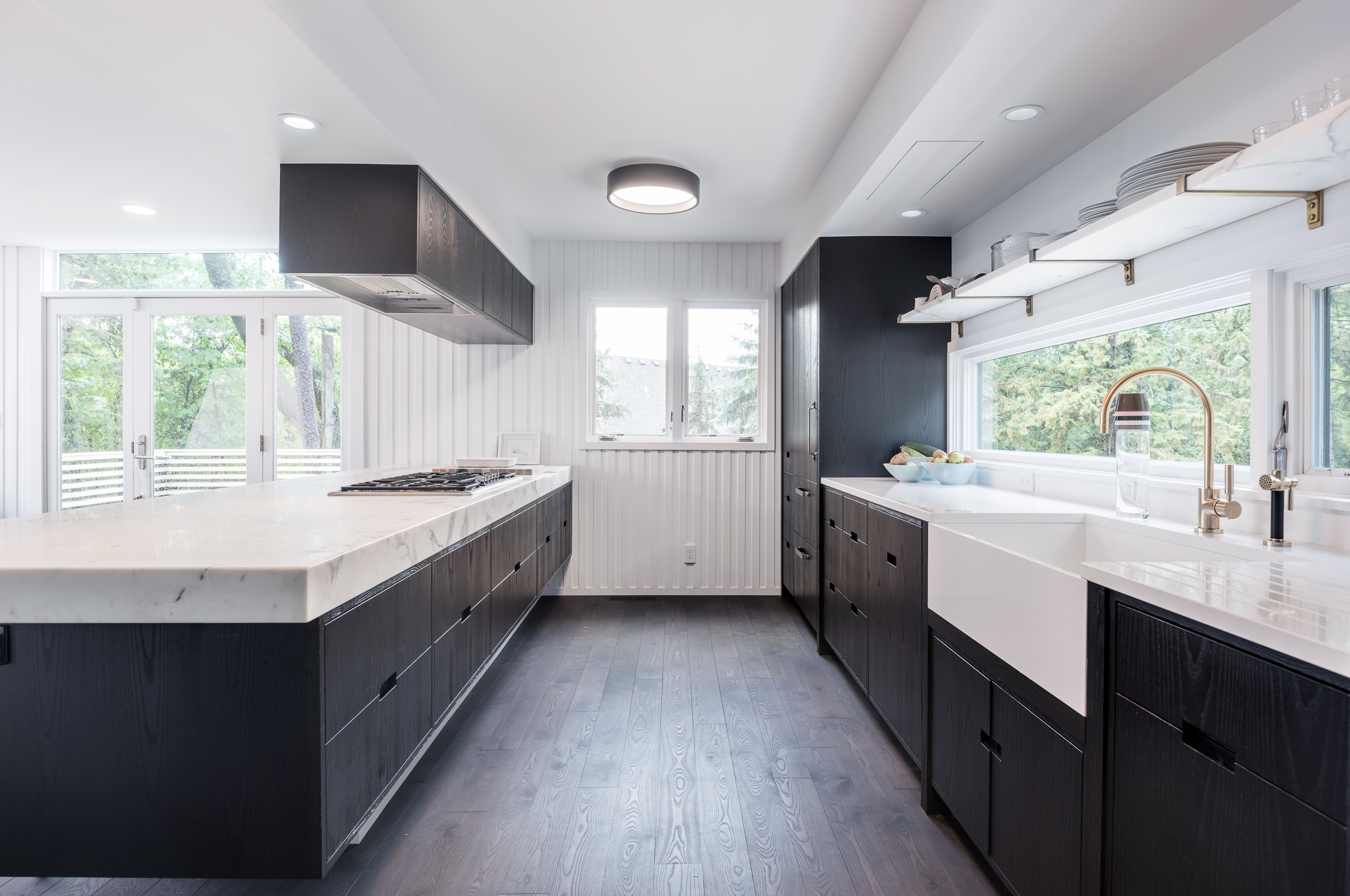 Modern kitchen renovation with dark cabinetry and thick marble countertop