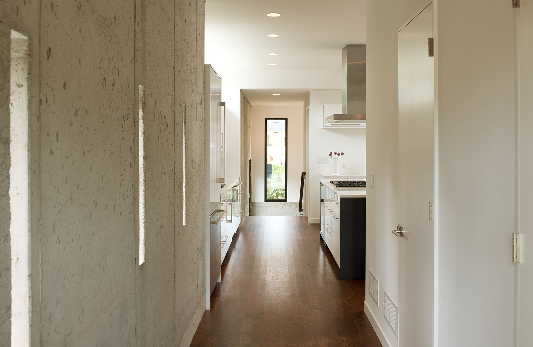 Hallway through kitchen on modern home remodel with exposed concrete wall