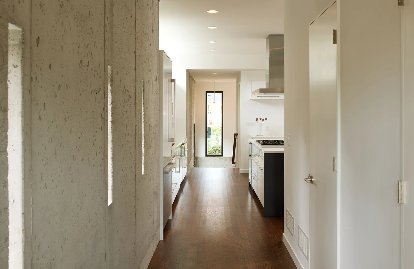 Hallway through kitchen on modern home remodel with exposed concrete wall