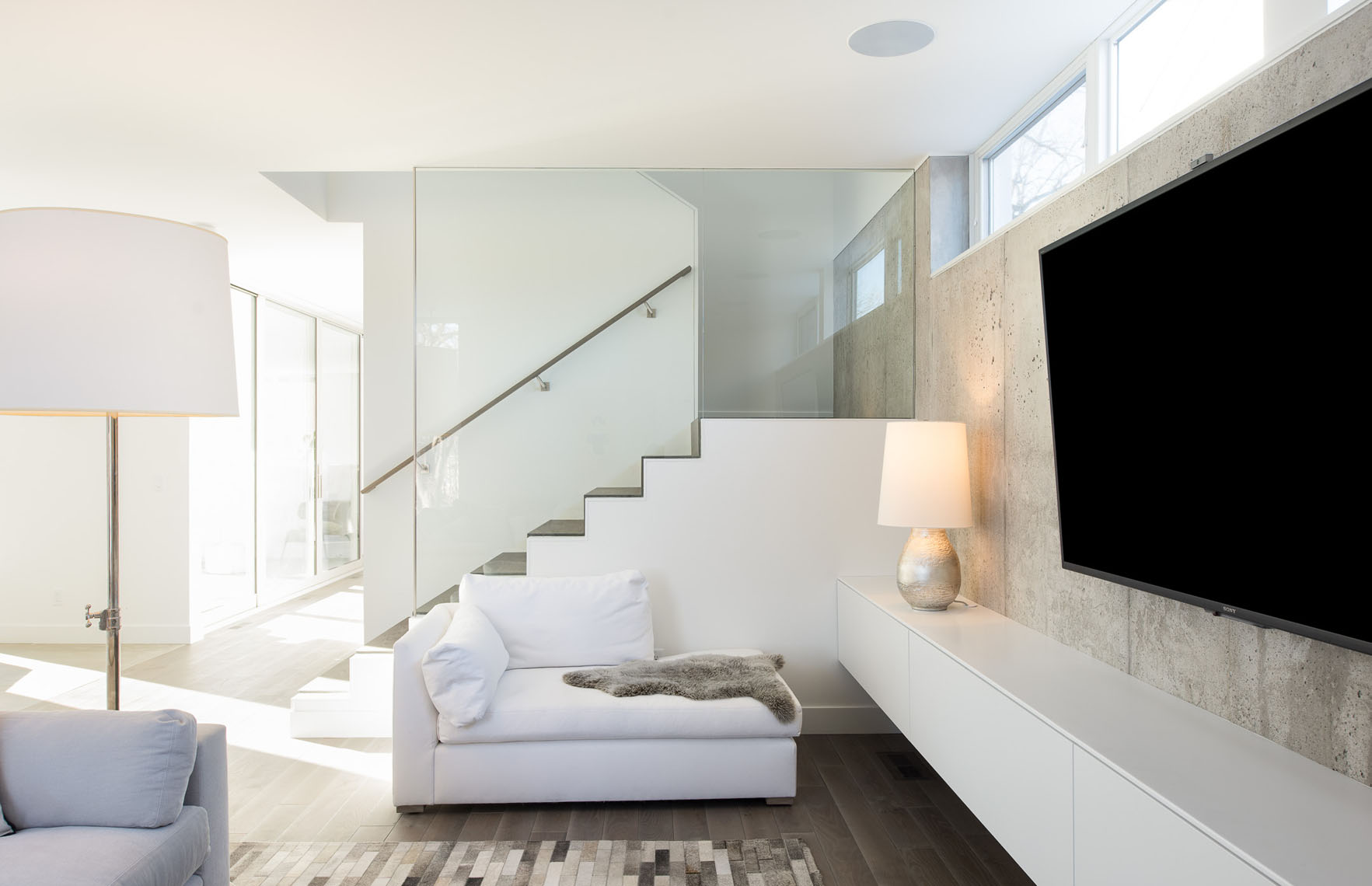 Modern living room with exposed concrete and a glass stair divider