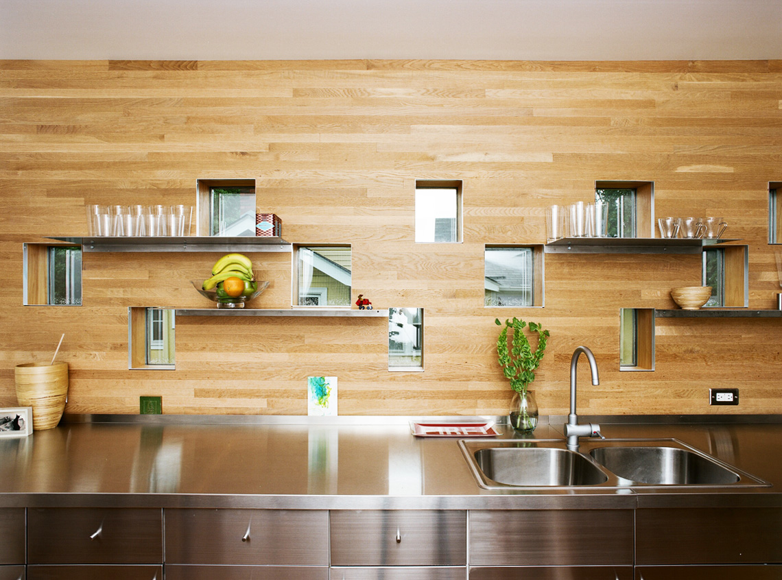 Kitchen counter with steel top and wood backsplash and custom windows