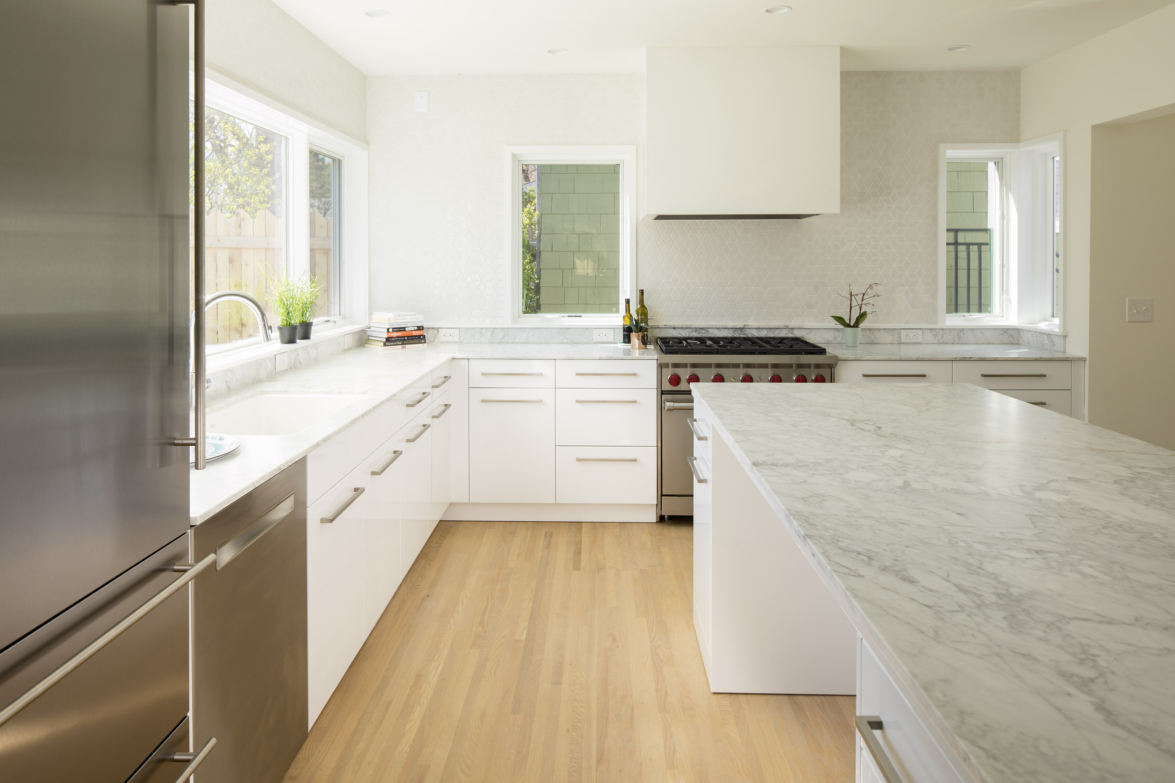Modern white kitchen remodel with marble countertops and tile backsplash