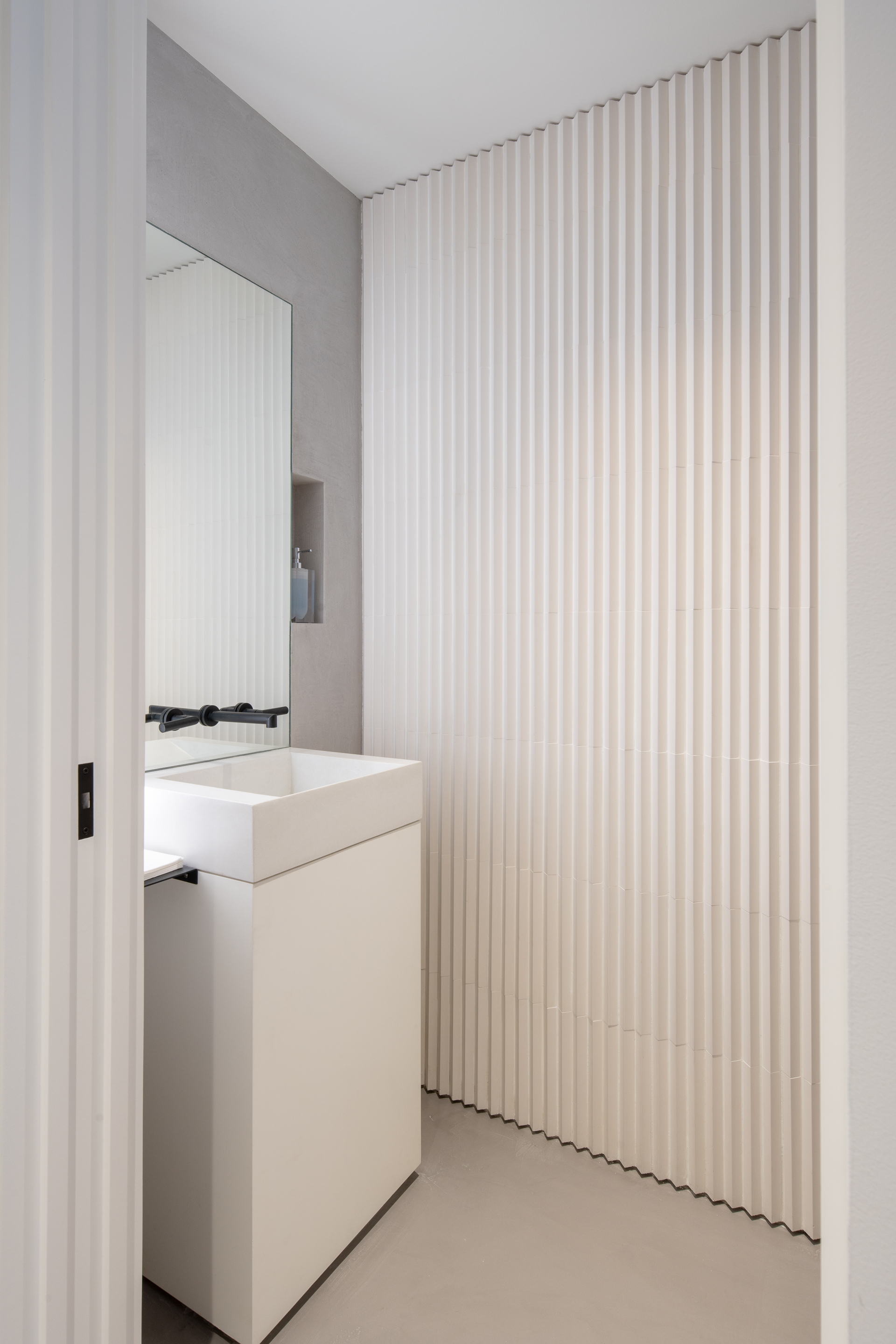 Modern powder room with geometric tile wall and custom soap niche