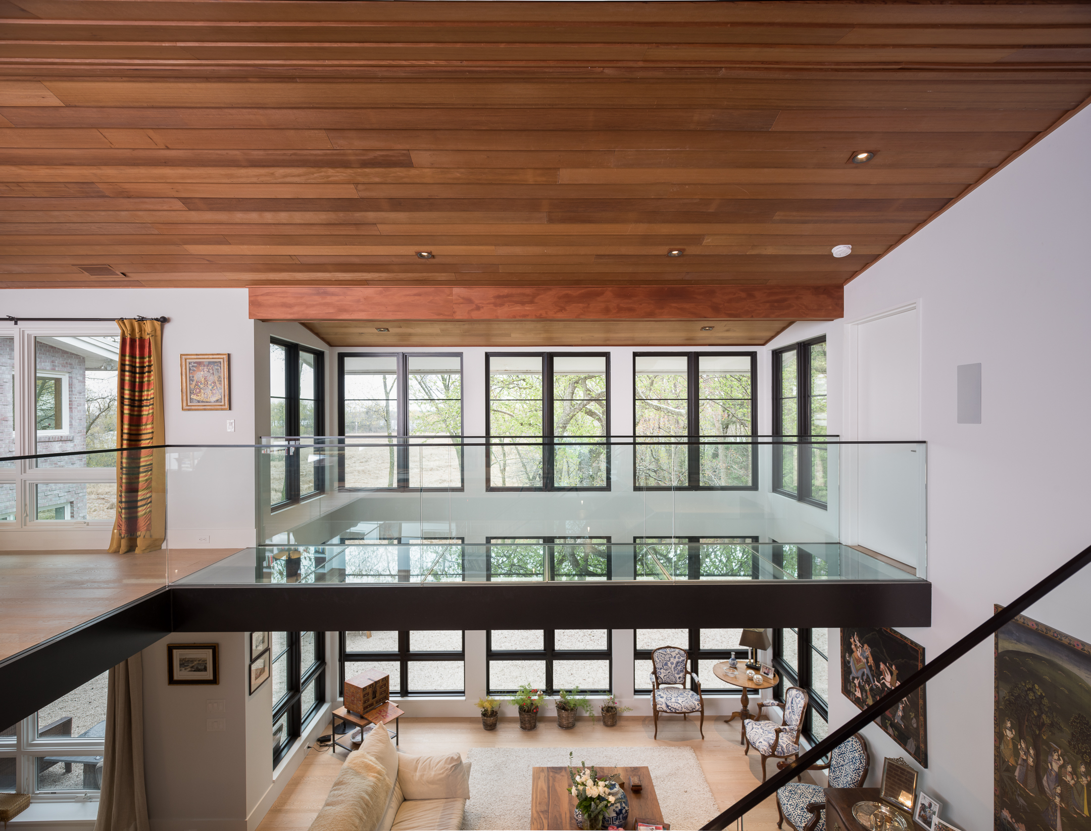 Custom interior glass bridge over vaulted living room 