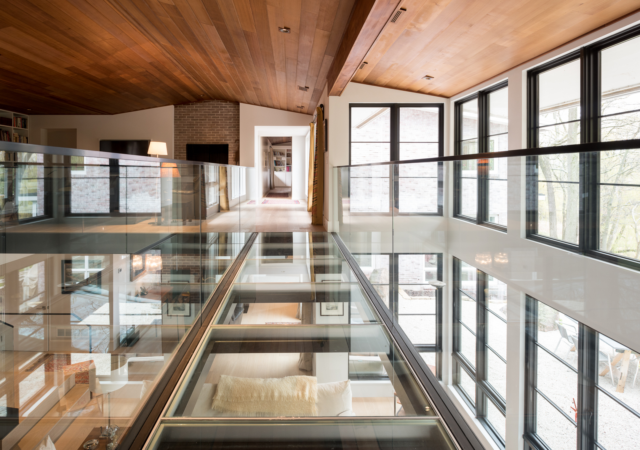 Custom interior glass bridge over vaulted living room 