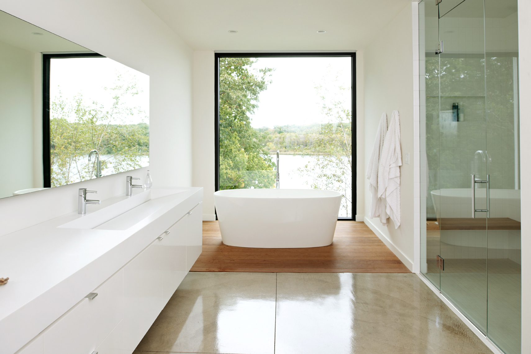 Minimal white master bathroom with soaking tub and picture window