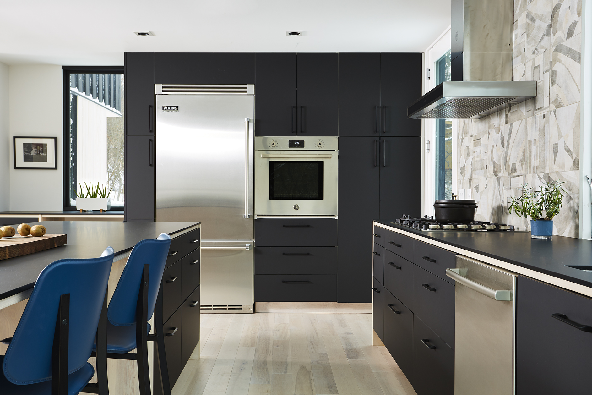 Modern monochromatic kitchen renovation with black cabinetry and wood accents