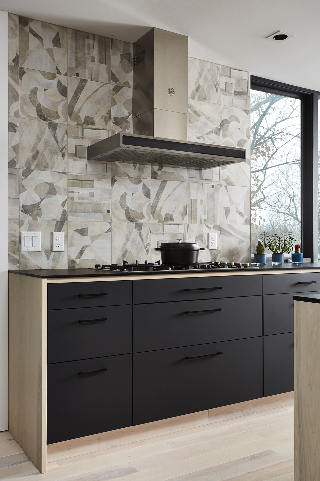 Black and wood cabinetry detail with graphic backsplash tile behind range