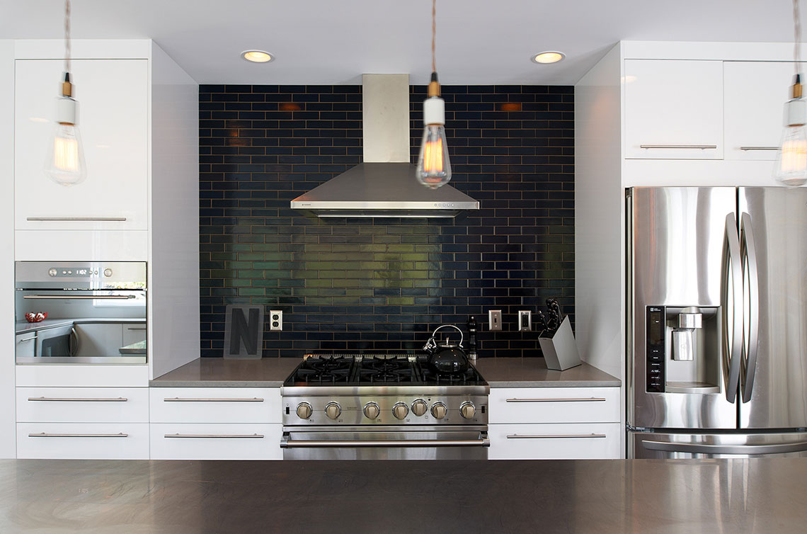 Modern monochromatic kitchen renovation with white cabinetry and black subway tile backsplash