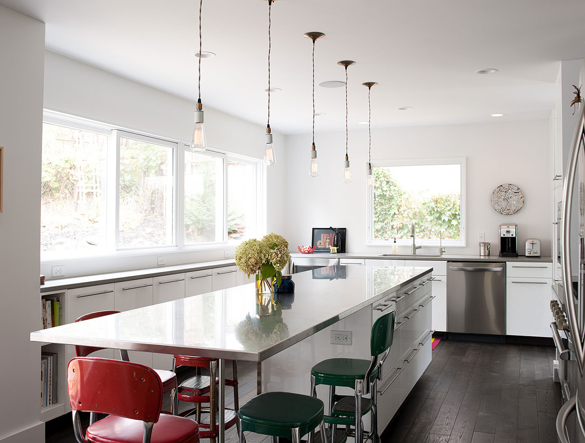 Modern white kitchen renovation with edison bulbs over large center island