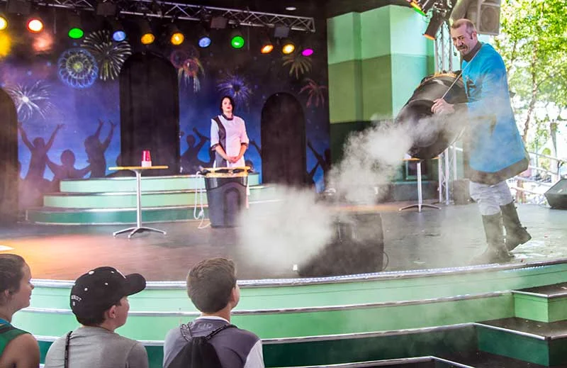 A smoke vortex ring rolling off the stage toward students at a science assembly