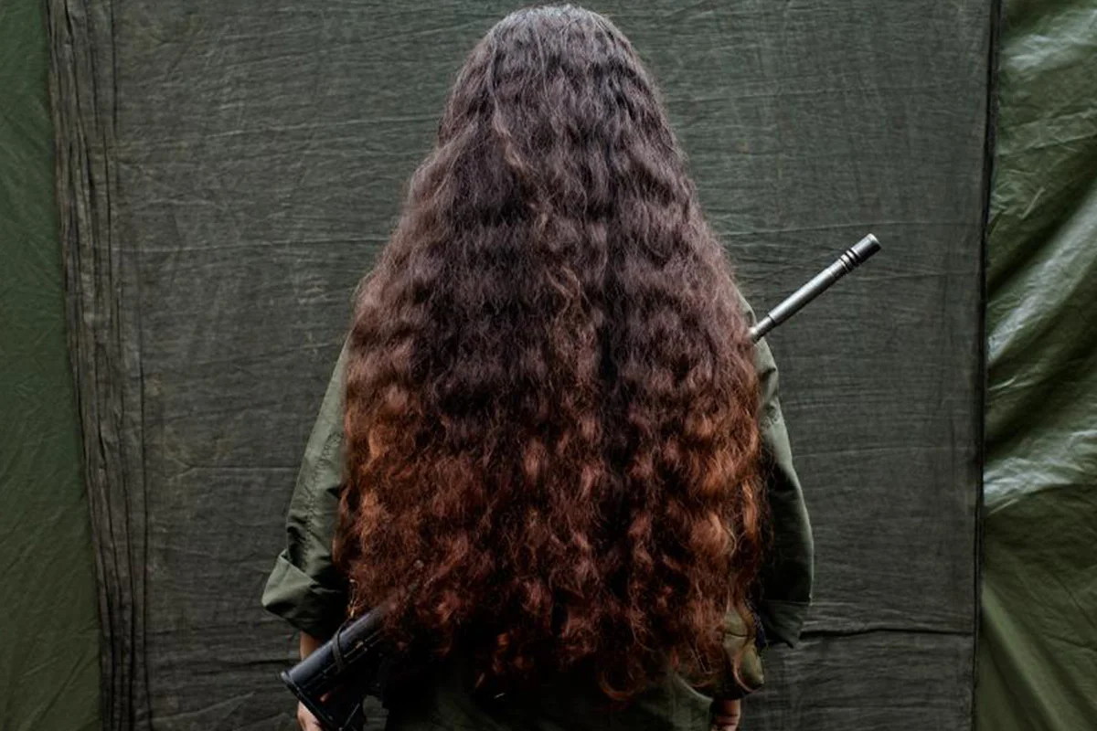 A shot from a woman's back with her hair covering a gun from Rape as a Weapon of War in the DRC episode. 