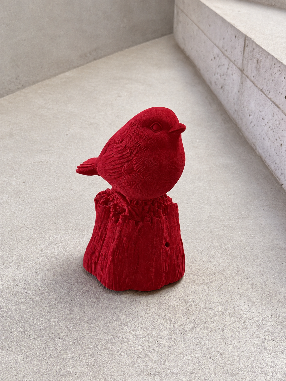 Figura de pájaro rojo sobre pedestal.png