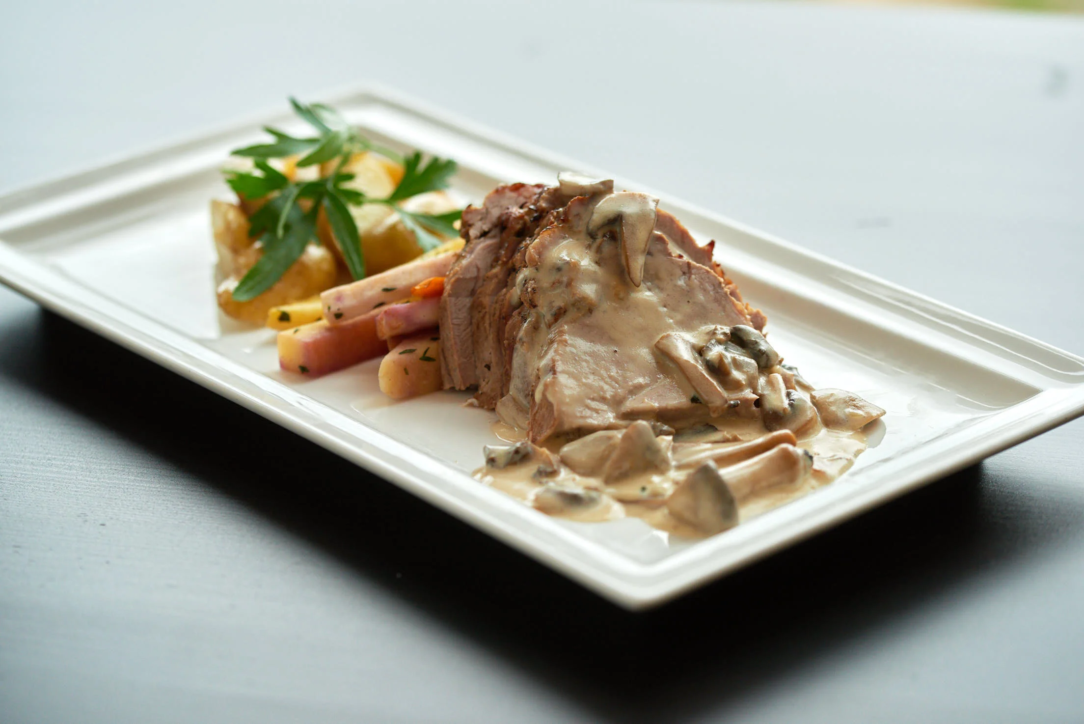 Servering av biff med sopp, potetstappe og grønnsaker.