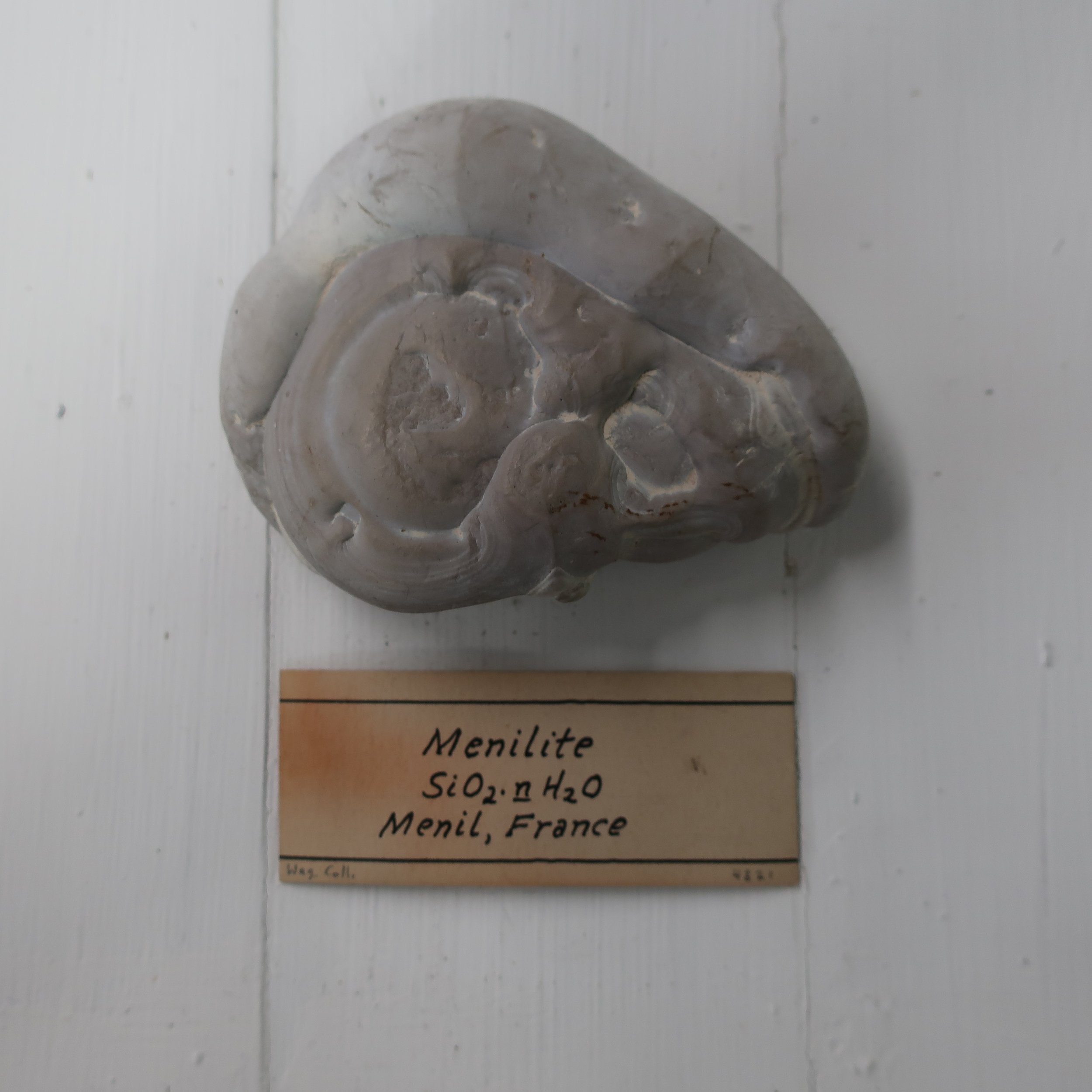   “Menelite  is a variety of semiopal occuring in compact reniform masses of a brown colour, structure slaty, found in beds of adhesive state at Menil-montant near Paris. It contains 85 silica, 1 alumina, and 11 water.” 