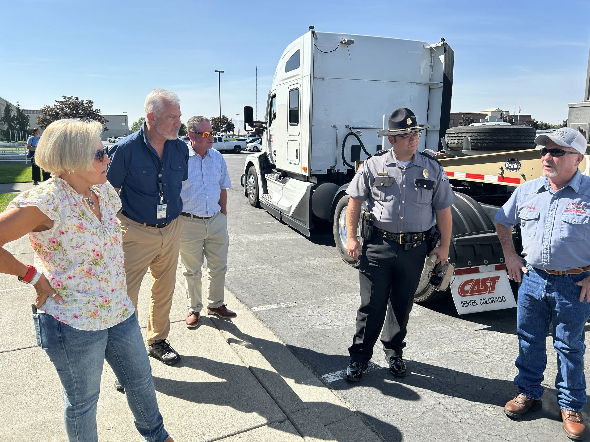 Several people ask a truck driver questions as he stands in front of the example truck and TRU canisters on trailer.