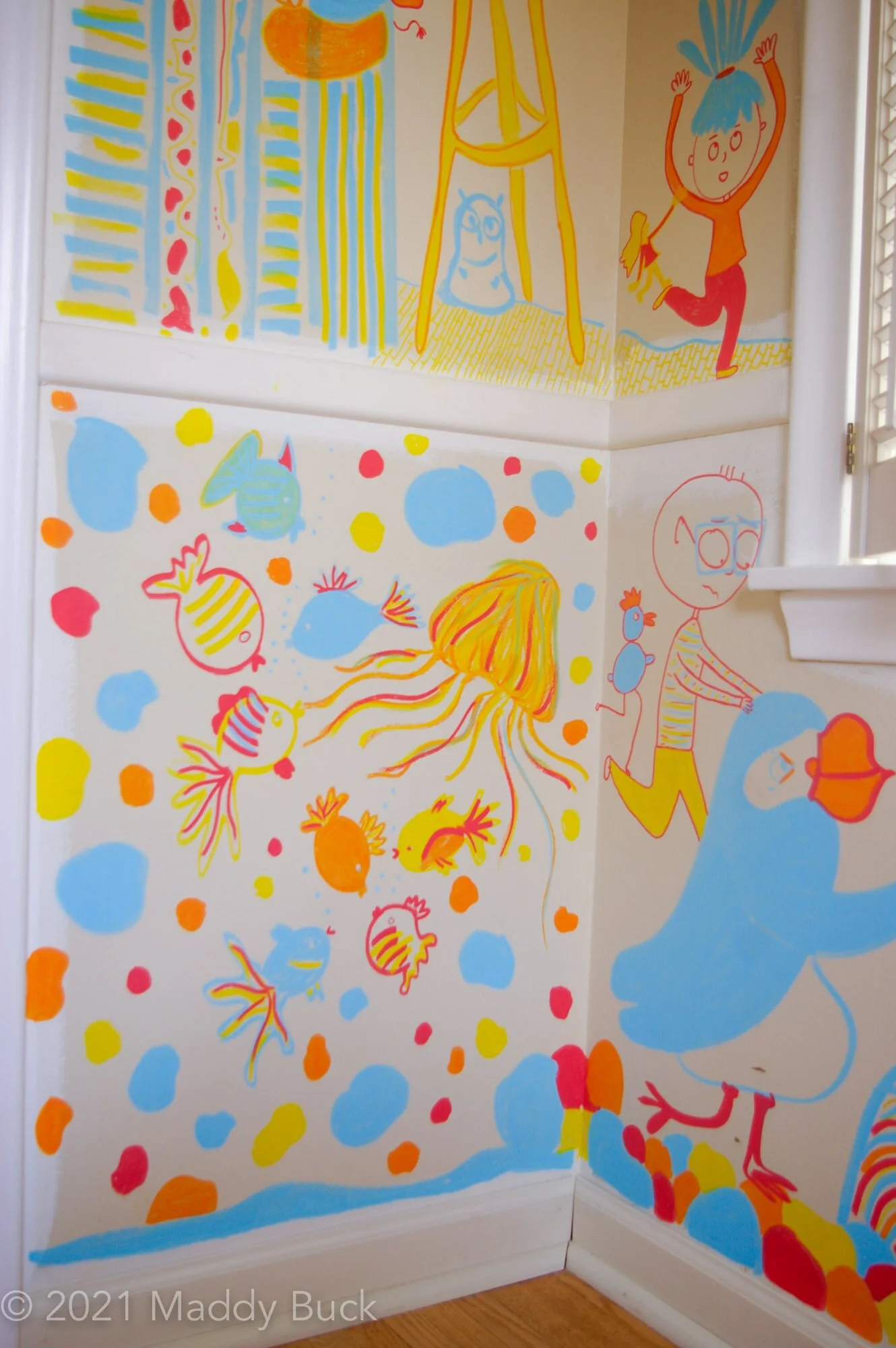  In this photo we see the bottom part of a mural in a kid’s bedroom. Most of the view is of an underwater scene, which includes a jelly fish and many fish. There are also lots of floating blobs in the scene. To the right of the underwater scene is a 