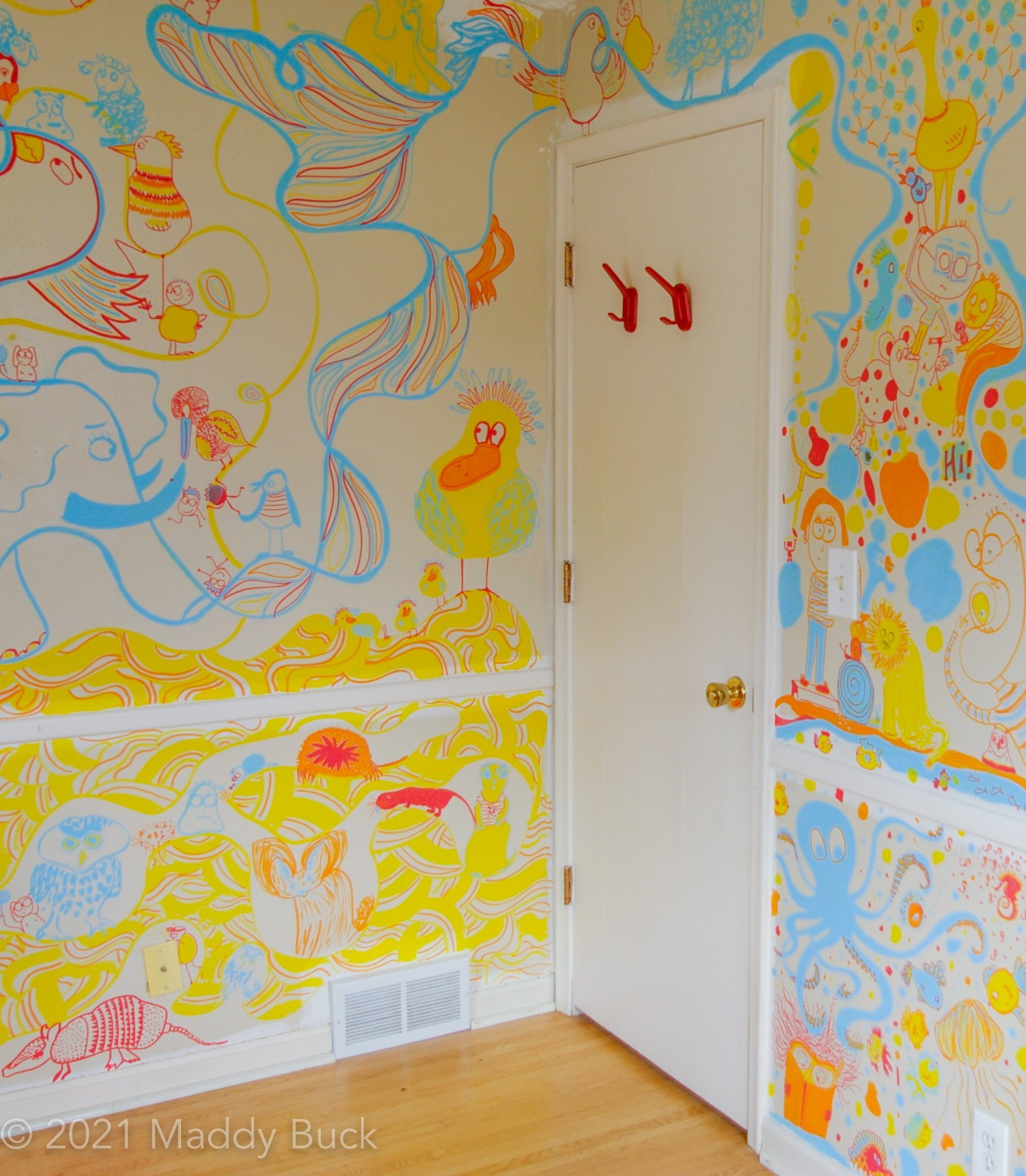  This photograph shows a nursery mural covering an entire bedroom. We can see many animals on the wall, including an enormous bird with huge wings that have colorful stripes. There is a large yellow duck with an orange beak, part of an elephant, and 