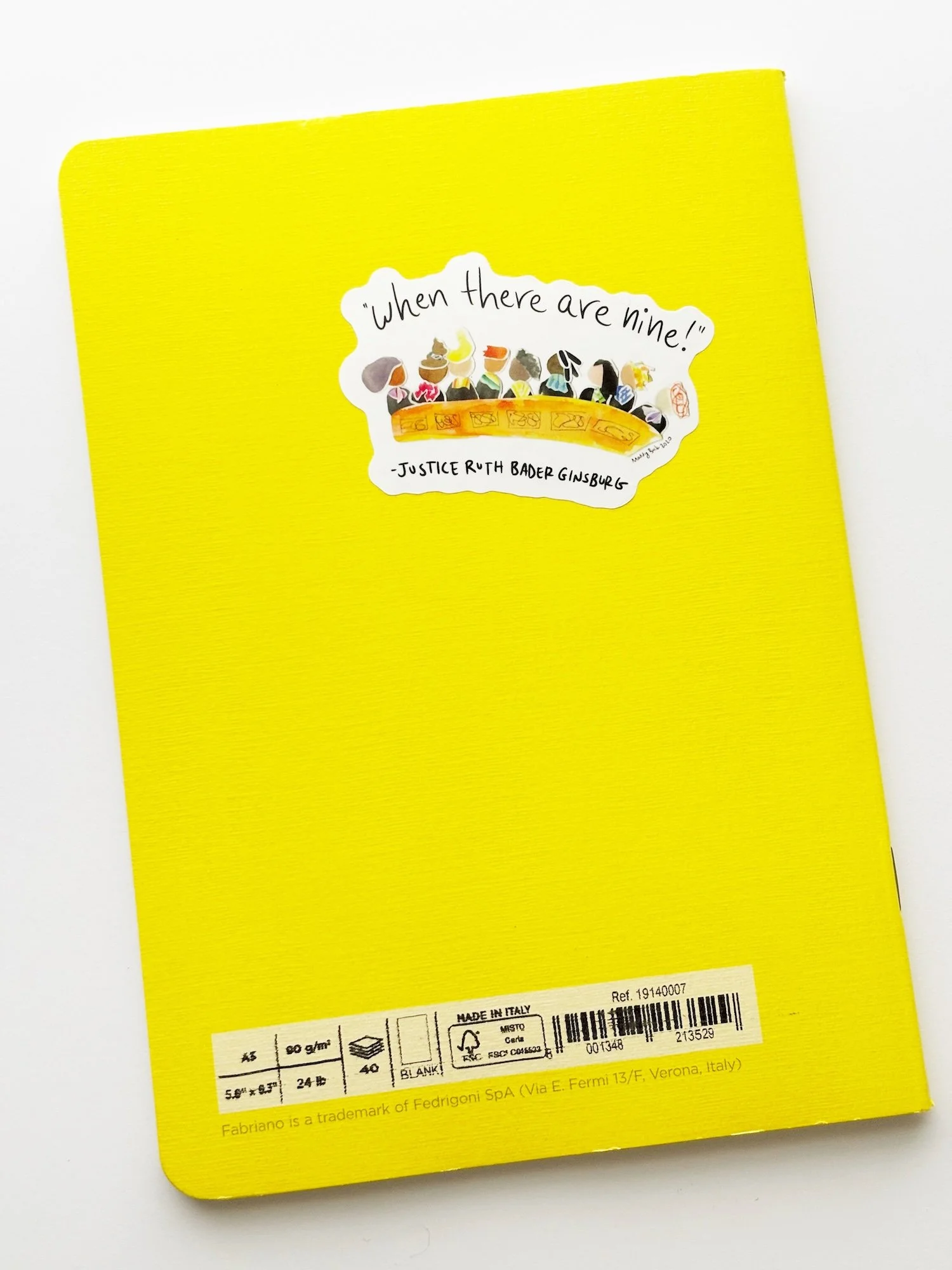  Photo of the back of a yellow sketchbook, where at the top on the right, we can see an example of the “when there are nine” sticker that shows a possible U.S. Supreme Court of entirely women.  
