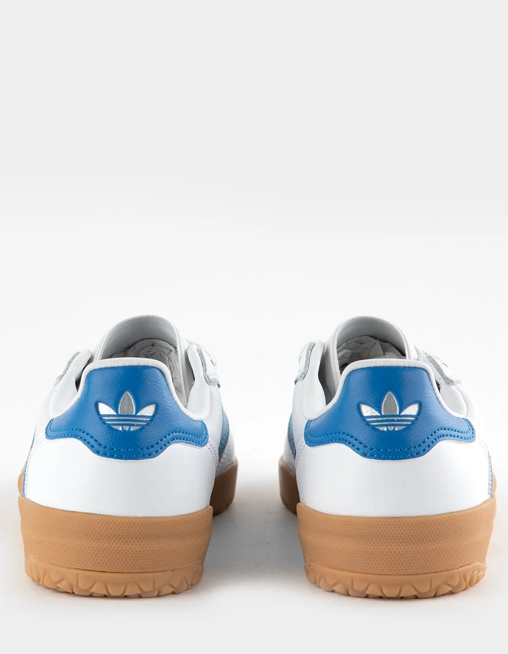 Rear view of white sneakers with blue accents and tan soles, featuring the Adidas Trefoil logo on the heel.