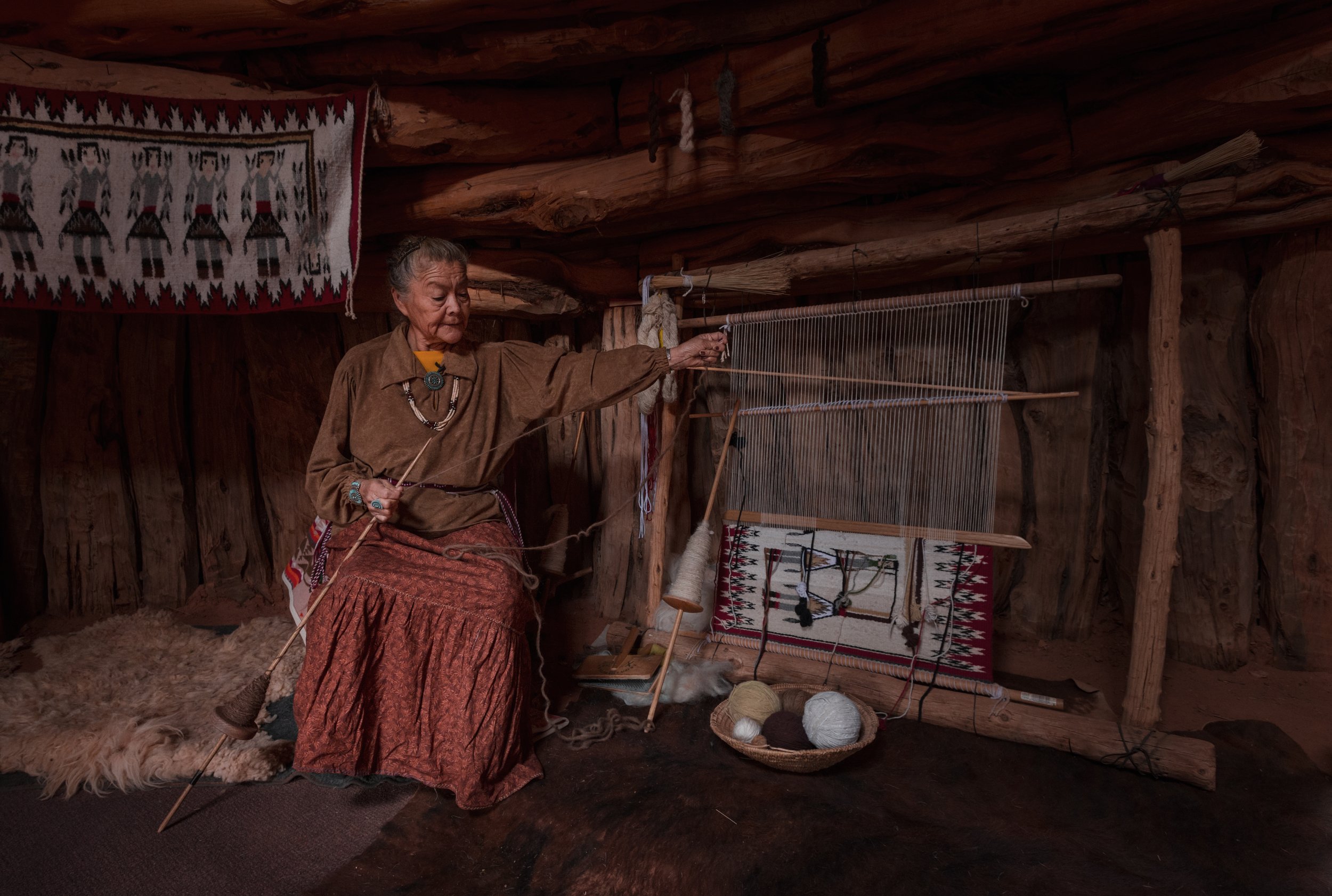  Effie Yazzie stretches her yarn from her spindle to prepare it being weaved into the rug 